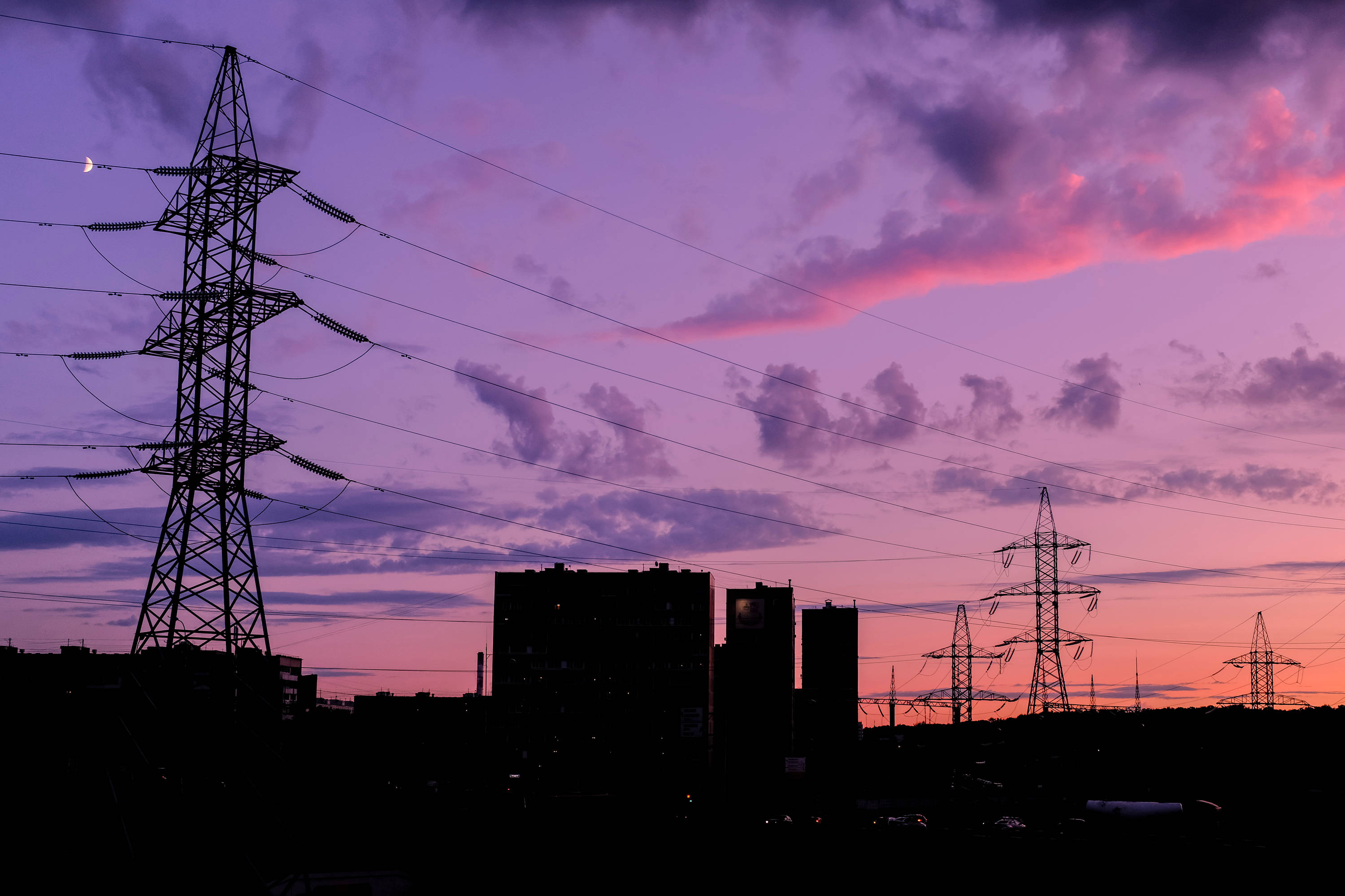 power outage 桌布 壁紙 — 電線和建築物的剪影，襯托著充滿活力的紫色和粉紅色日落天空，伴隨著一彎新月。