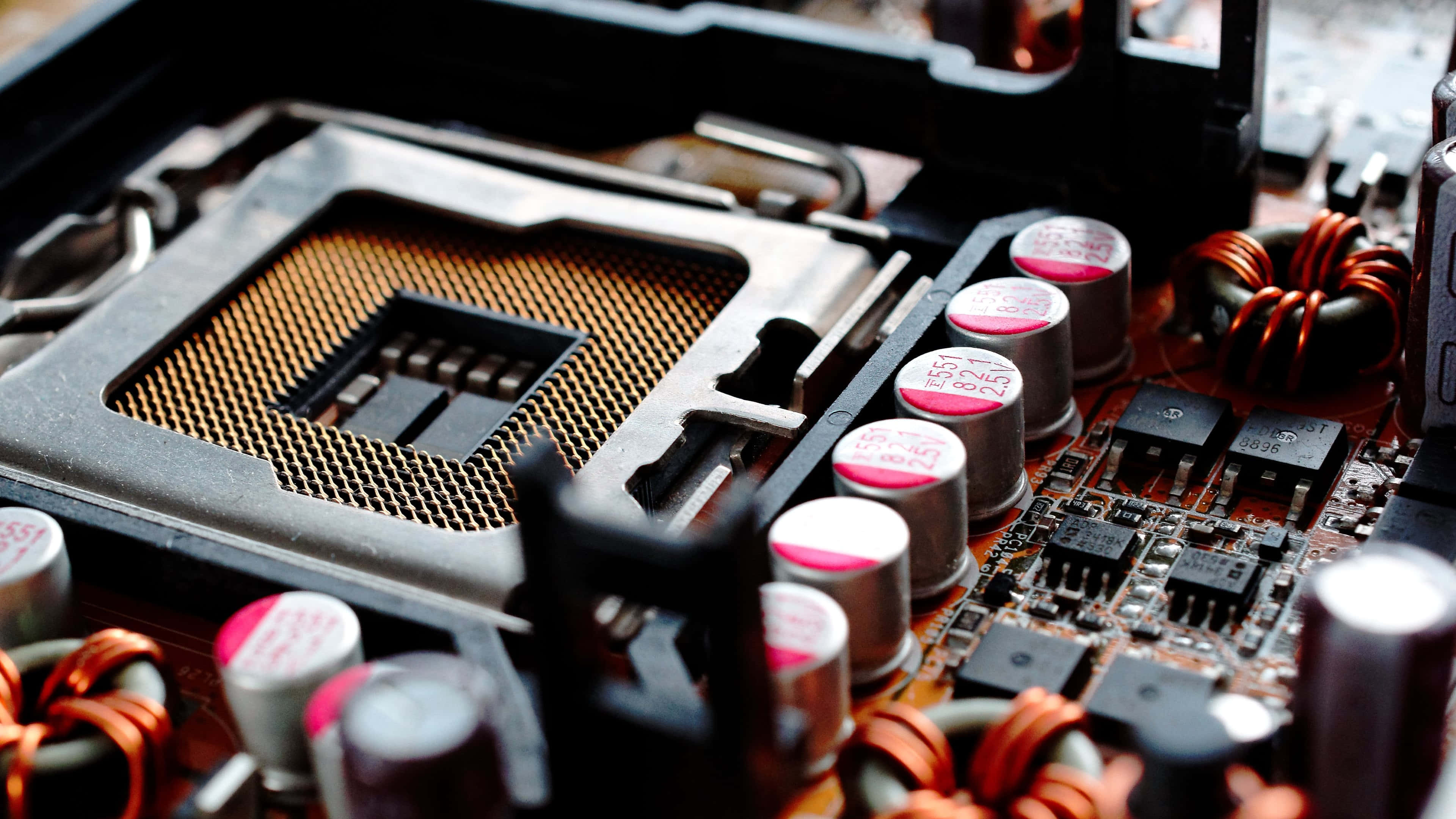 Electronic Components 桌布 壁紙 — 電腦主機板特寫，顯示CPU插槽、電容器和銅線圈，景深較淺。
