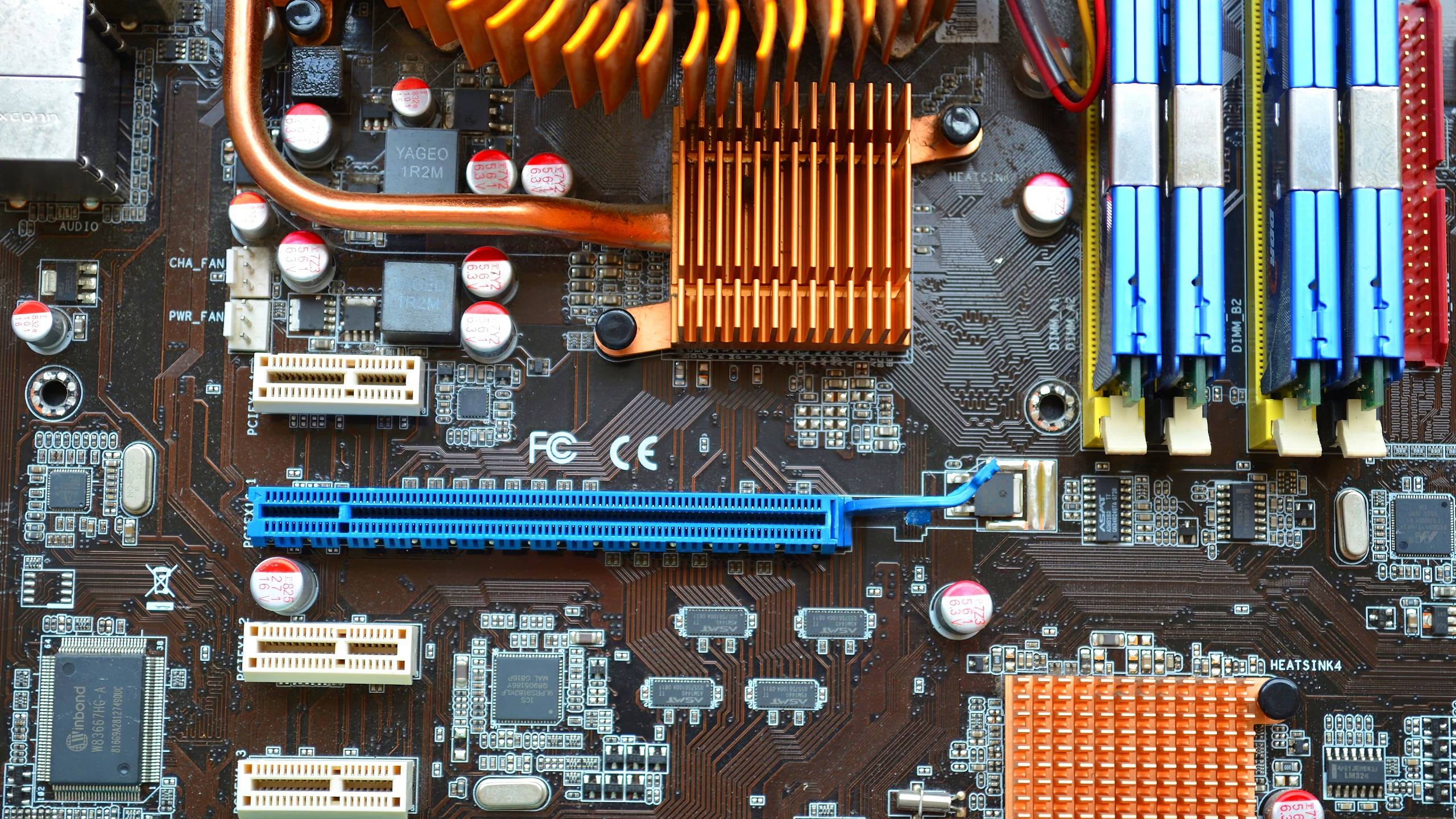 Motherboard 桌布 壁紙 — 電腦主機板特寫，顯示銅製散熱器、藍色RAM插槽和複雜電路。