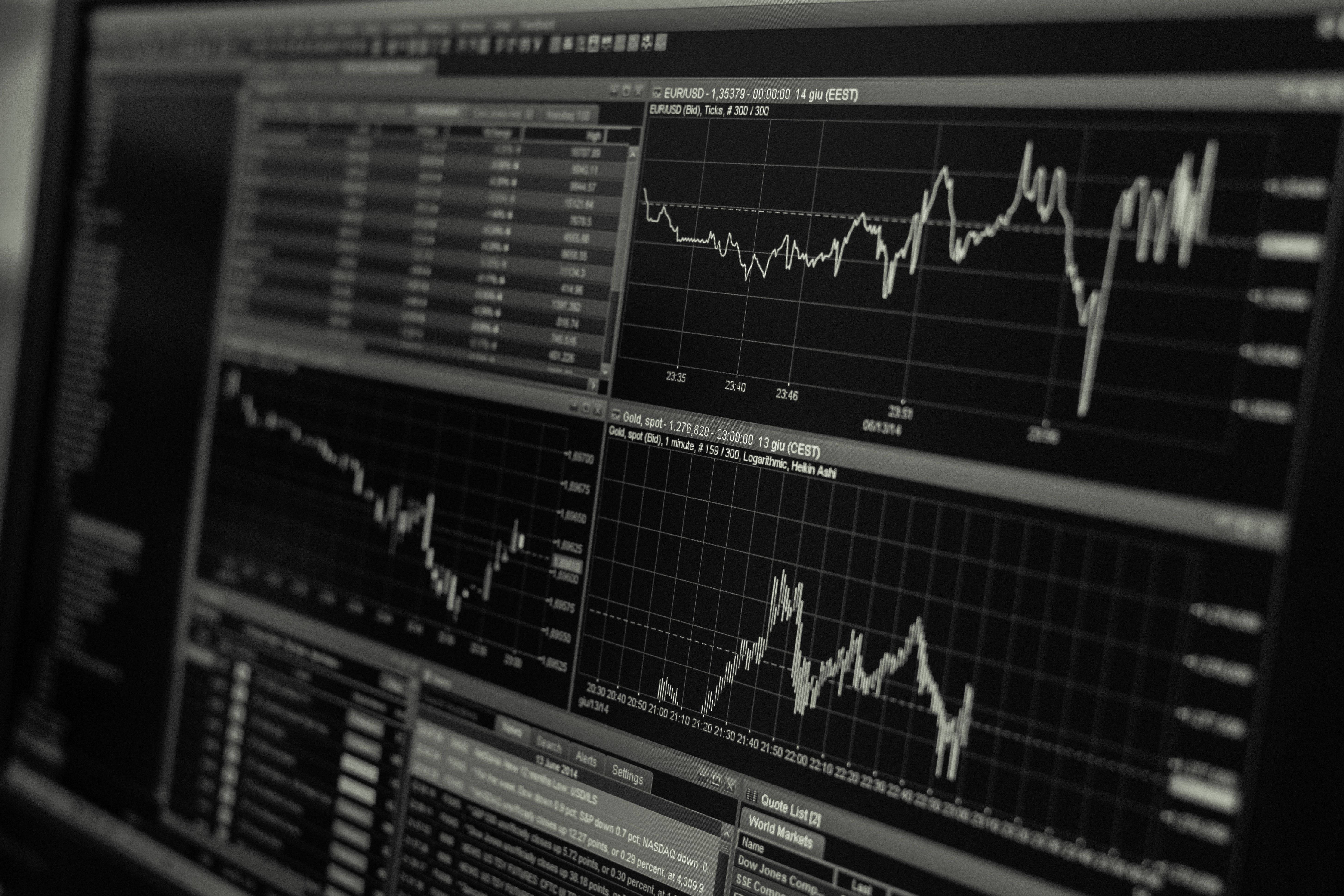 Market 桌布 壁紙 — 電腦顯示器特寫，顯示多個波動的金融圖表和數據流，採用單色調。