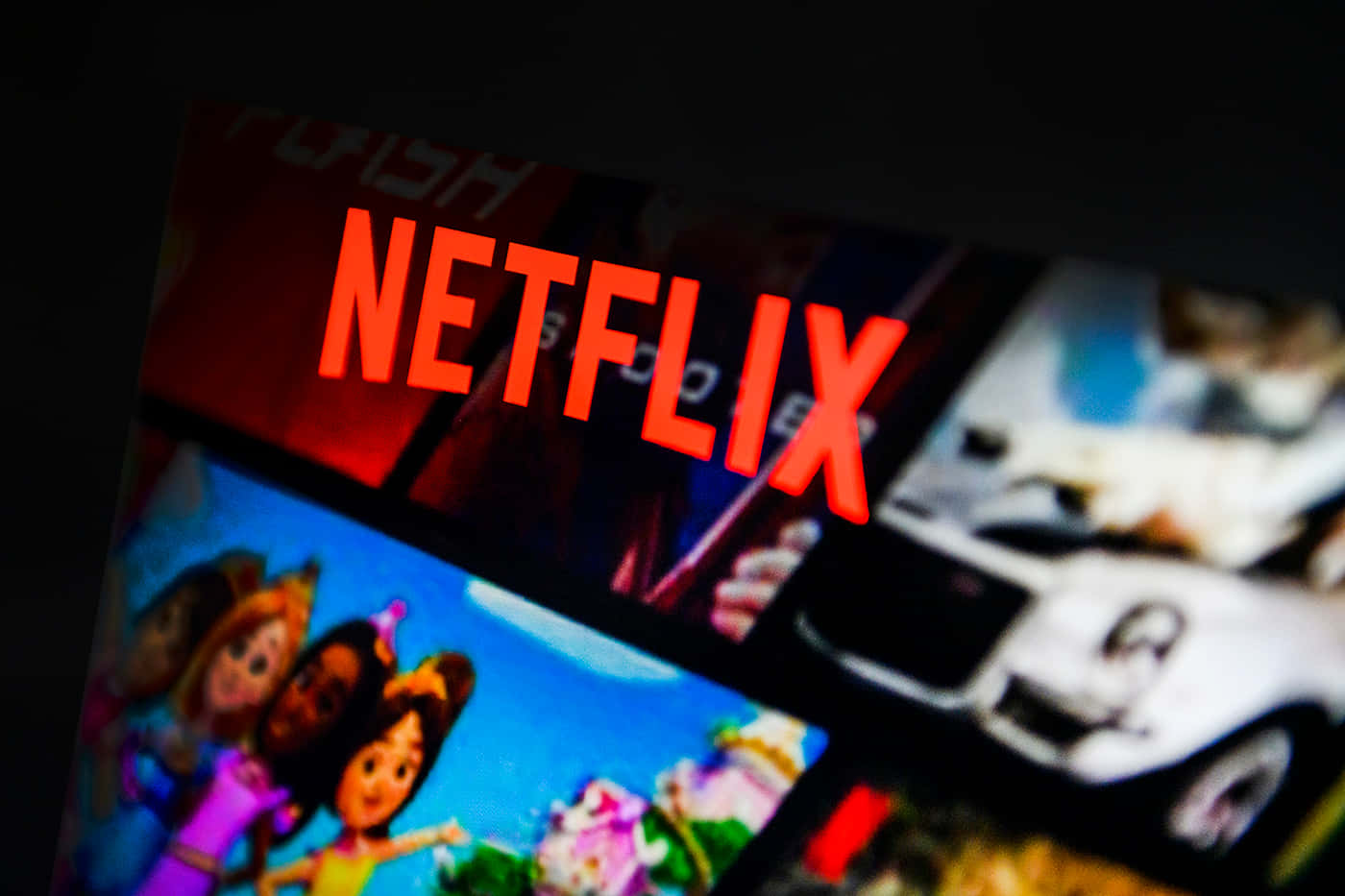 Netflix 桌布 壁紙 — 電視螢幕特寫，顯示Netflix標誌發出紅色光芒，下方有模糊的電影縮圖。