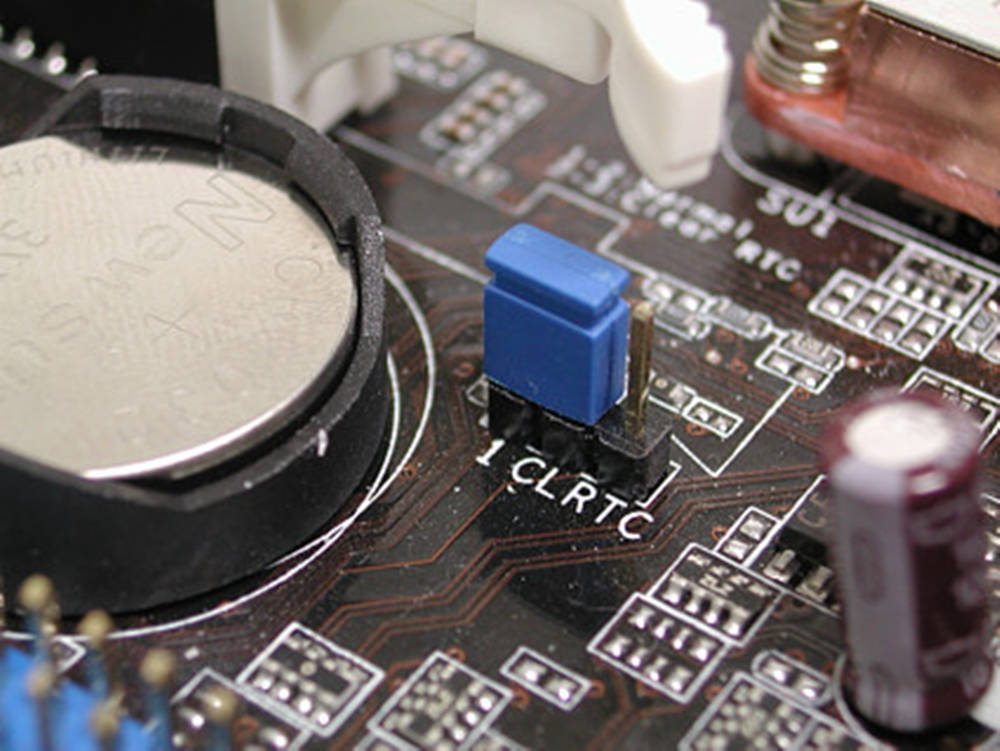 Motherboard 桌布 壁紙 — 電路板特寫，帶有藍色電容和銀色硬幣電池安裝在複雜的銅跡上。