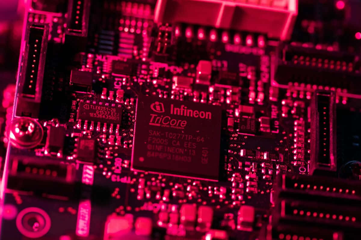 Electronic Components 桌布 壁紙 — 電路板特寫，沐浴在強烈的粉紅色光線中，突顯複雜的電子元件和文字。