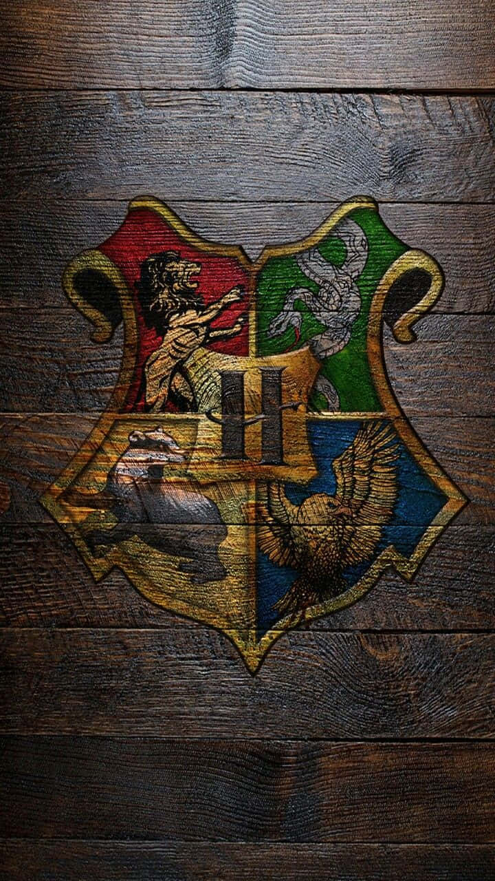 Hogwarts Crest 桌布 壁紙 — 霍格華茲學校徽章，上有獅子、老鷹、獾和蛇的標誌，背景為風化的深色木材。
