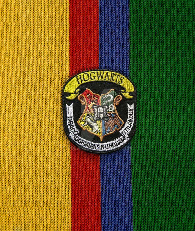 Hogwarts Crest 桌布 壁紙 — 霍格華茲徽章刺繡在黃、紅、藍、綠垂直條紋針織毛衣上的特寫。