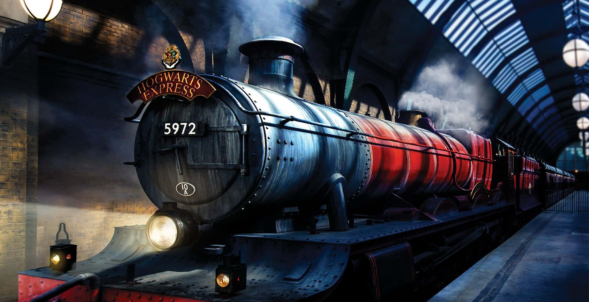 The Hogwarts Express Train 桌布 壁紙 — 霍格華茲特快車的蒸汽火車頭在車站燈光下閃耀，帶有紅色和銀色條紋，煙霧在宏偉的拱形大廳中翻騰。
