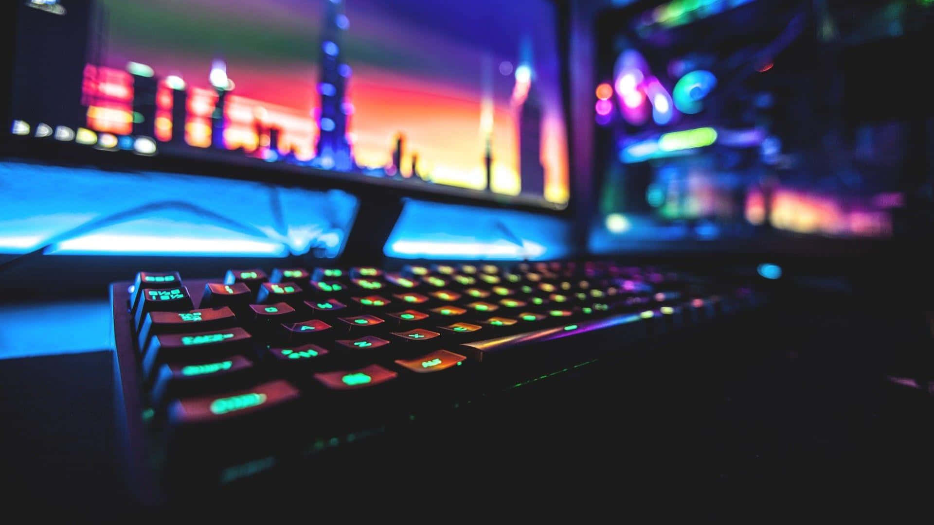 Gaming Setup 桌布 壁紙 — 霓虹燈下，前景有一個發光的RGB鍵盤，後面顯示器上模糊的城市景觀。