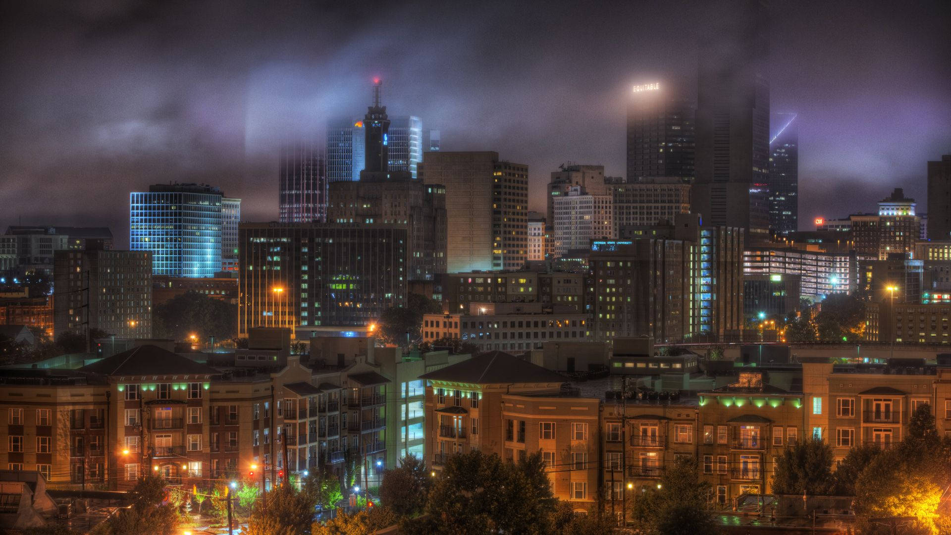 Atlanta 桌布 壁紙 — 霧夜城市景觀，閃爍的摩天大樓和溫暖的路燈照亮了霧氣瀰漫的城市建築。