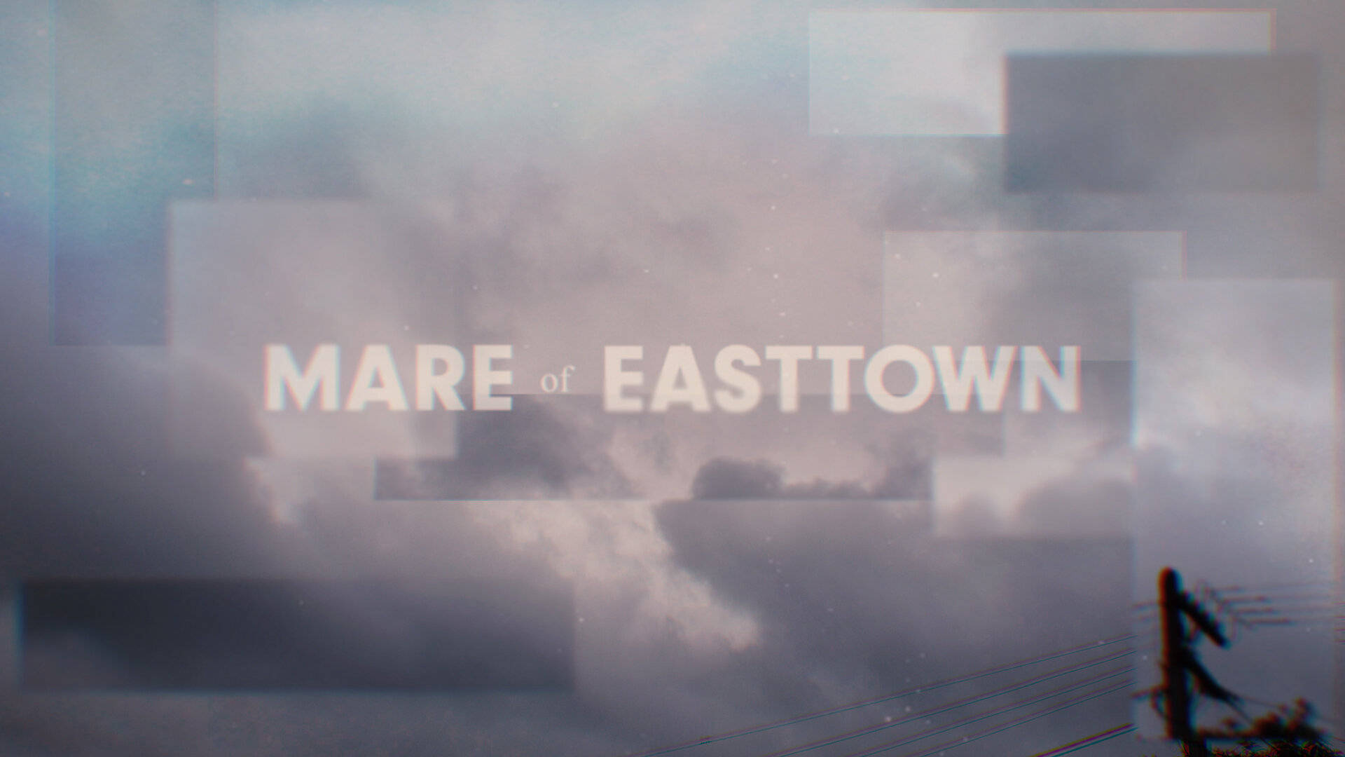 Mare 桌布 壁紙 — 霧氣瀰漫的城市景觀，帶有 'MARE of EASTTOWN' 文字疊加在柔和的灰色雲層和電線上。