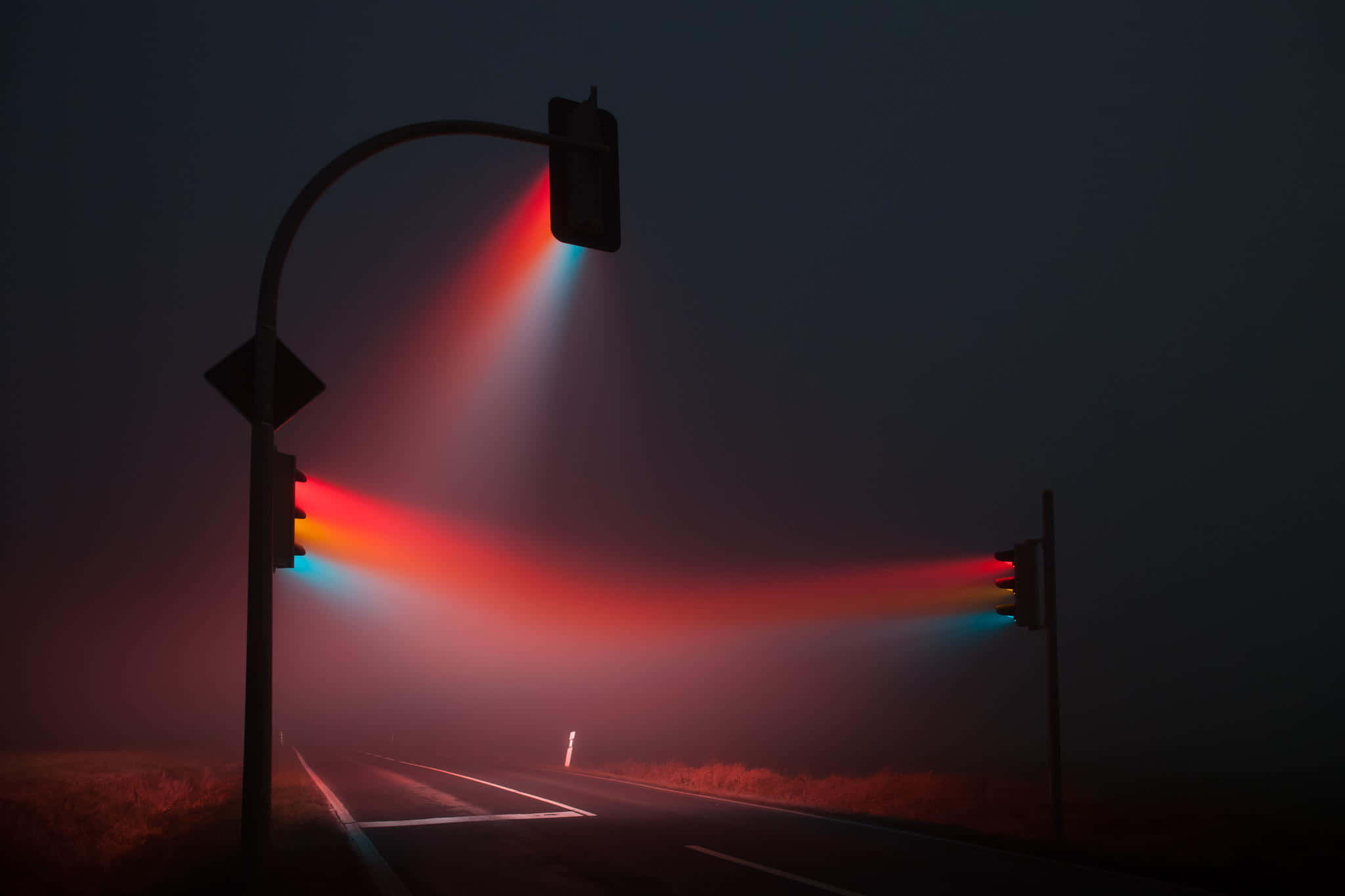 Street Light 桌布 壁紙 — 霧氣瀰漫的夜晚道路，被發光的紅色和藍色交通燈照亮，透過霧氣投射出戲劇性的光束。