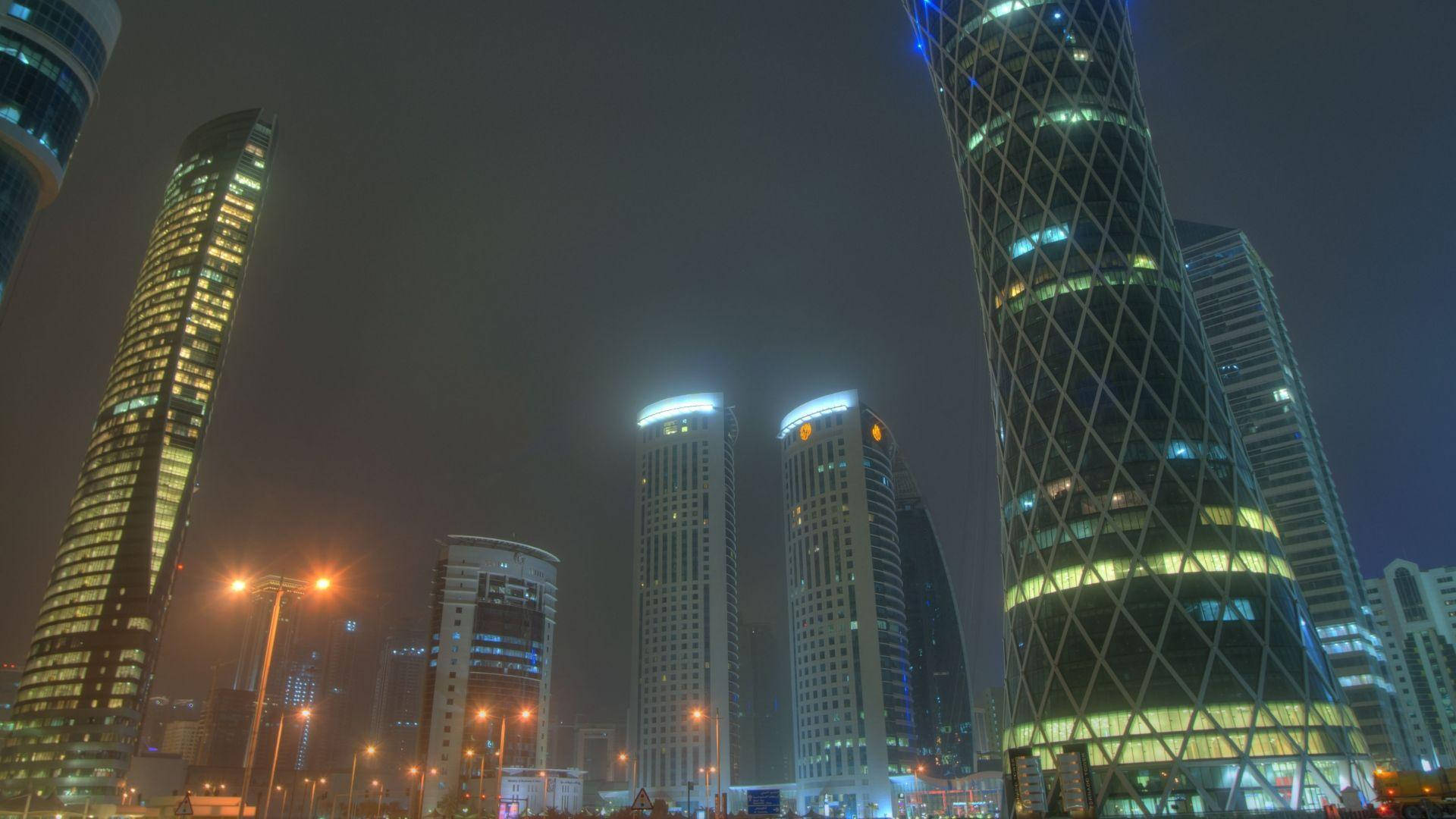 夜空 桌布 壁紙 — 霧氣瀰漫的夜景，高樓大廈和街燈在黑暗的天空中散發出溫暖的光芒。