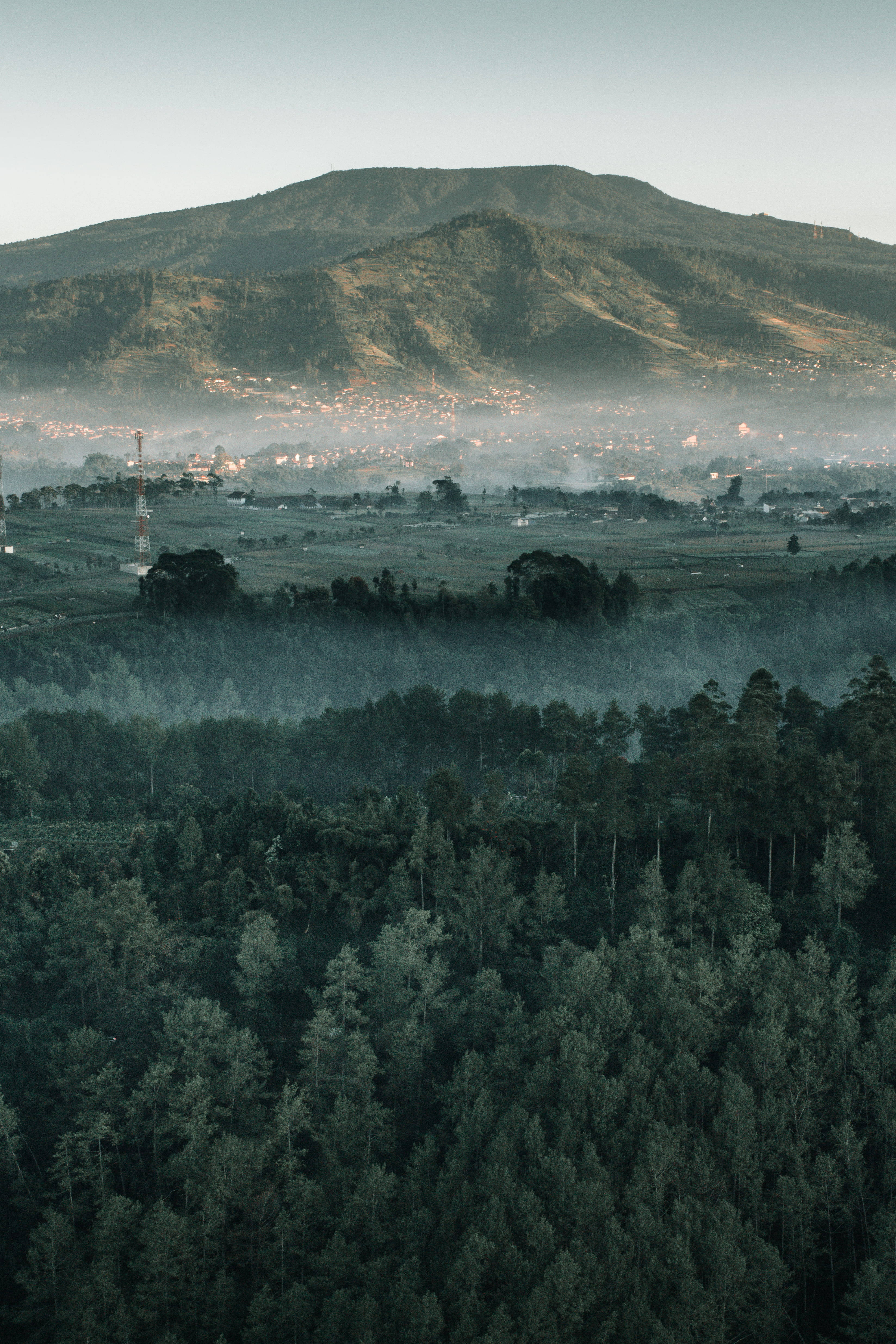bandung 桌布 壁紙 — 霧氣瀰漫的黎明景色，森林覆蓋的山谷，遠山和隱藏在薄霧中的小鎮。