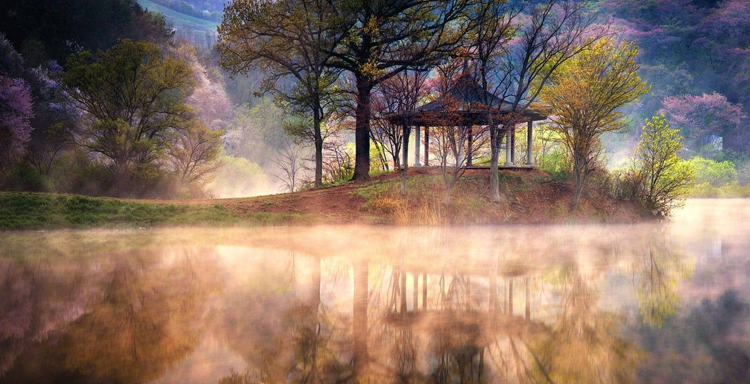 山脈 桌布 壁紙 — 霧氣瀰漫的黎明湖邊景色，一座木製涼亭坐落在色彩繽紛的樹木之間，在平靜的水面上柔和地倒映。