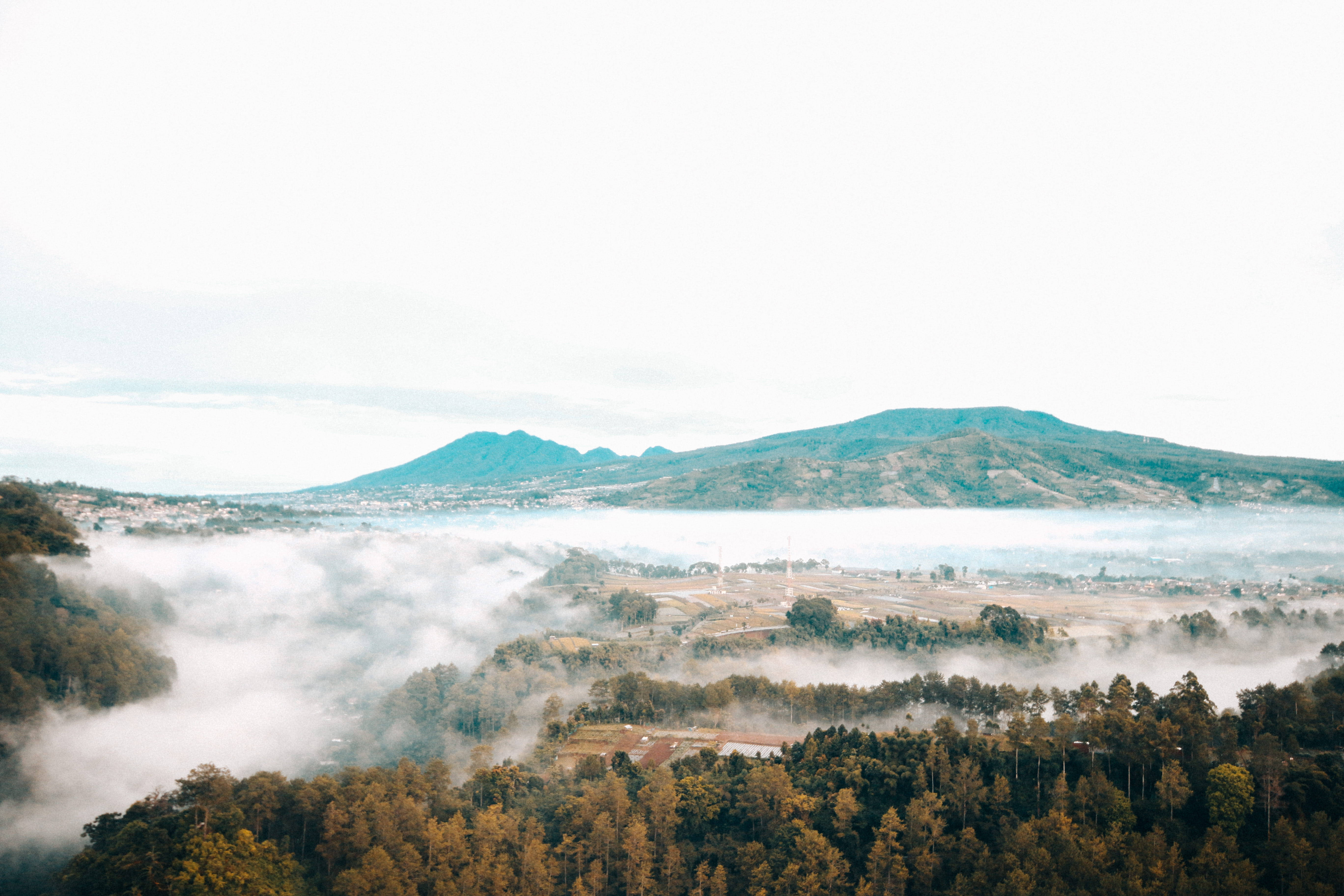 bandung 桌布 壁紙 — 霧氣籠罩的早晨，覆蓋著一個有森林和遠山的山谷，天空柔和多雲。