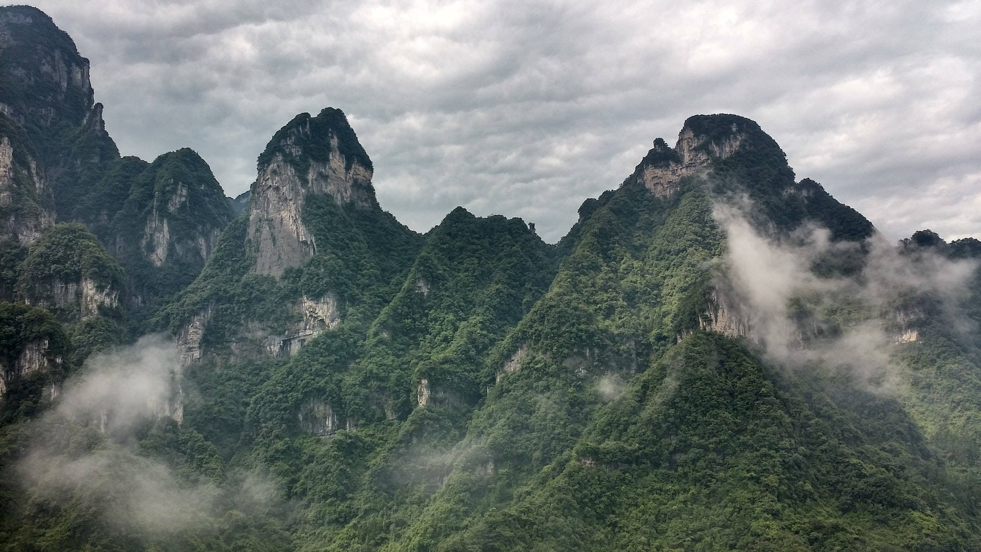 Mountain Landscape 桌布 壁紙 — 霧氣雲朵在陰天天空下飄過高聳的綠色山脈。