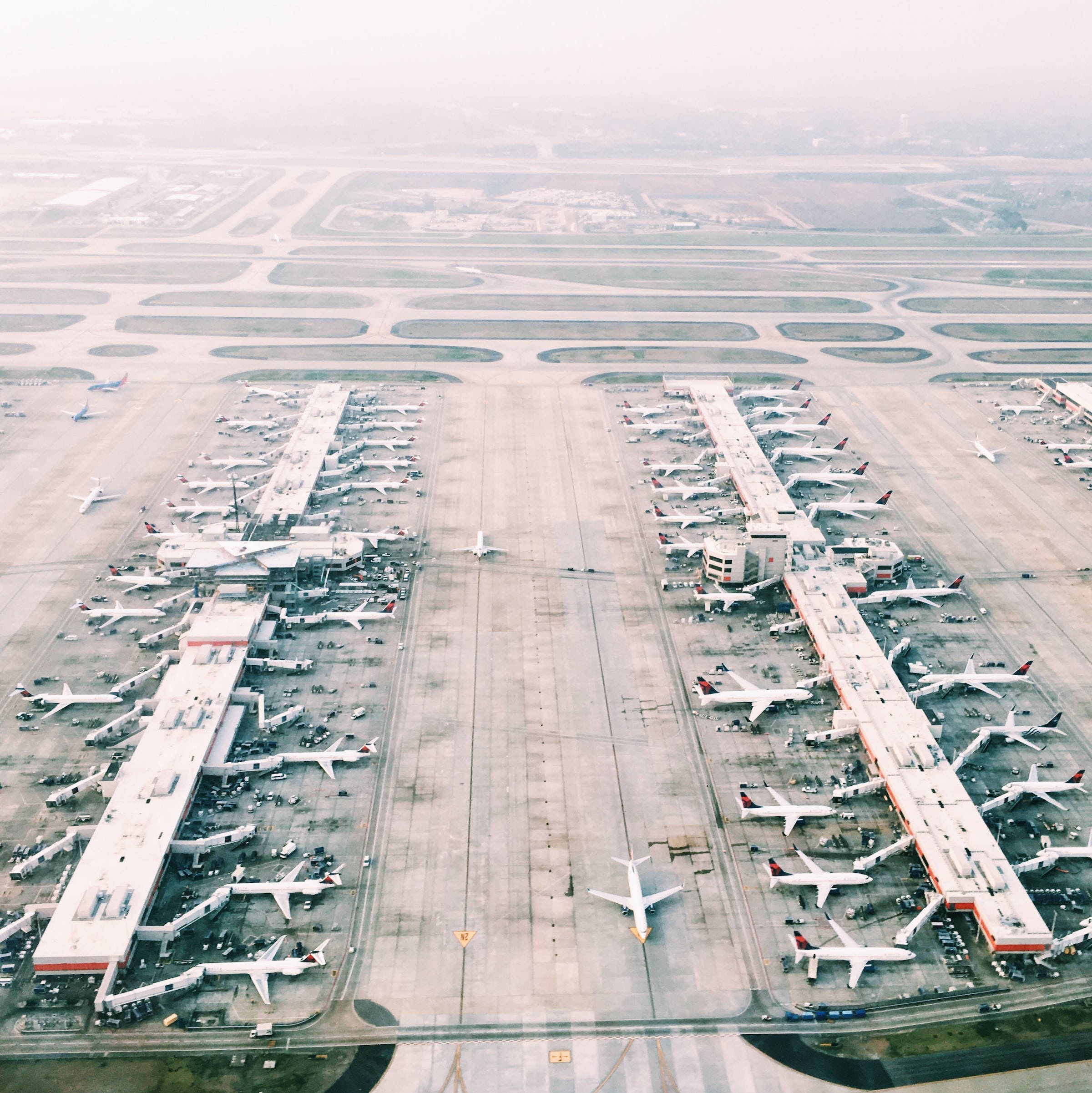 Airport 桌布 壁紙 — 霧濛濛的天空下，一個廣闊機場的鳥瞰圖，停機坪上排列著飛機和航廈。