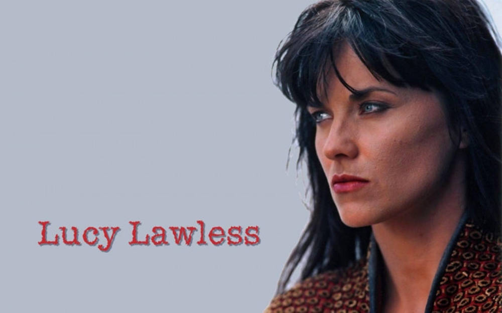 紫色 桌布 壁紙 — 露西·勞萊斯（Lucy Lawless）在純灰色背景上，深色頭髮和紅唇，名字以紅色文字顯示，目光專注。