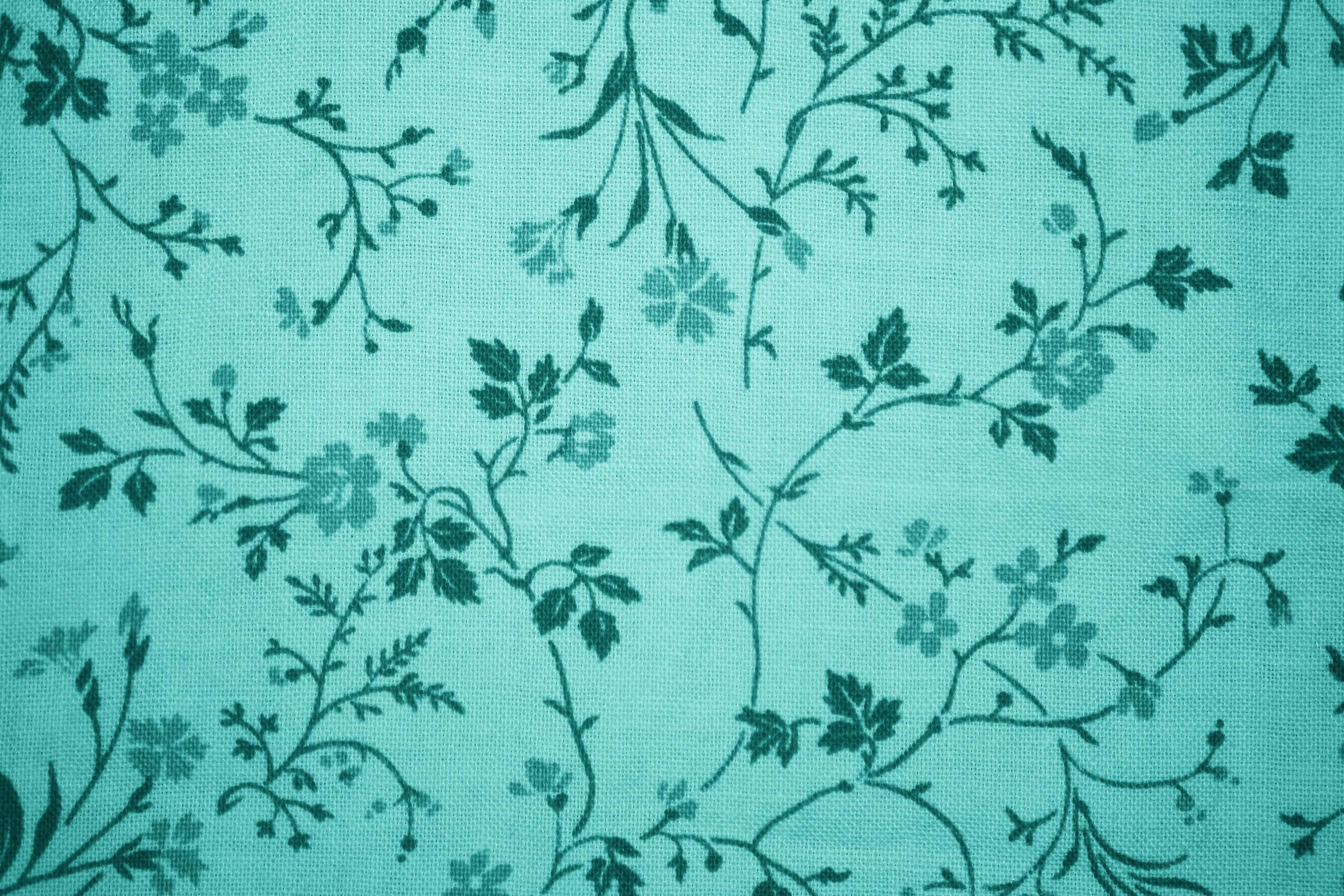 青色GIF 桌布 壁紙 — 青綠色布料的特寫，上面有深綠色的花藤和花朵，形成重複圖案。