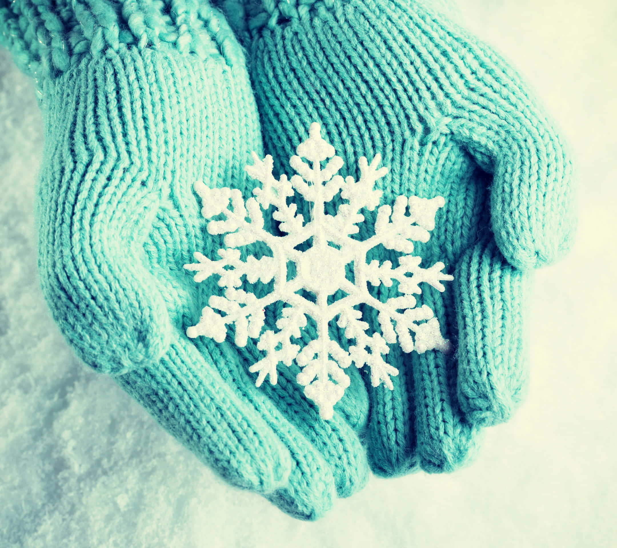 Mittens 桌布 壁紙 — 青色針織手套在雪景背景下輕托著一片精緻的白色雪花。