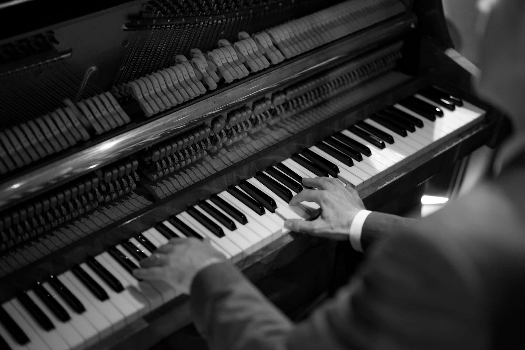Black And White Piano 桌布 壁紙 — 音樂家的手在戲劇性的黑白特寫中彈奏三角鋼琴，展現複雜的內部機制。