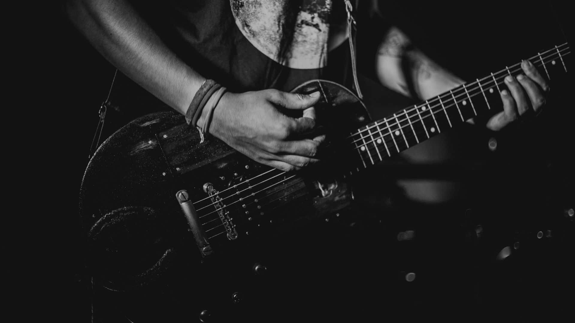 Black And White Guitar 桌布 壁紙 — 音樂家的雙手在單色戲劇性舞台燈光下熟練地彈奏黑色電吉他。