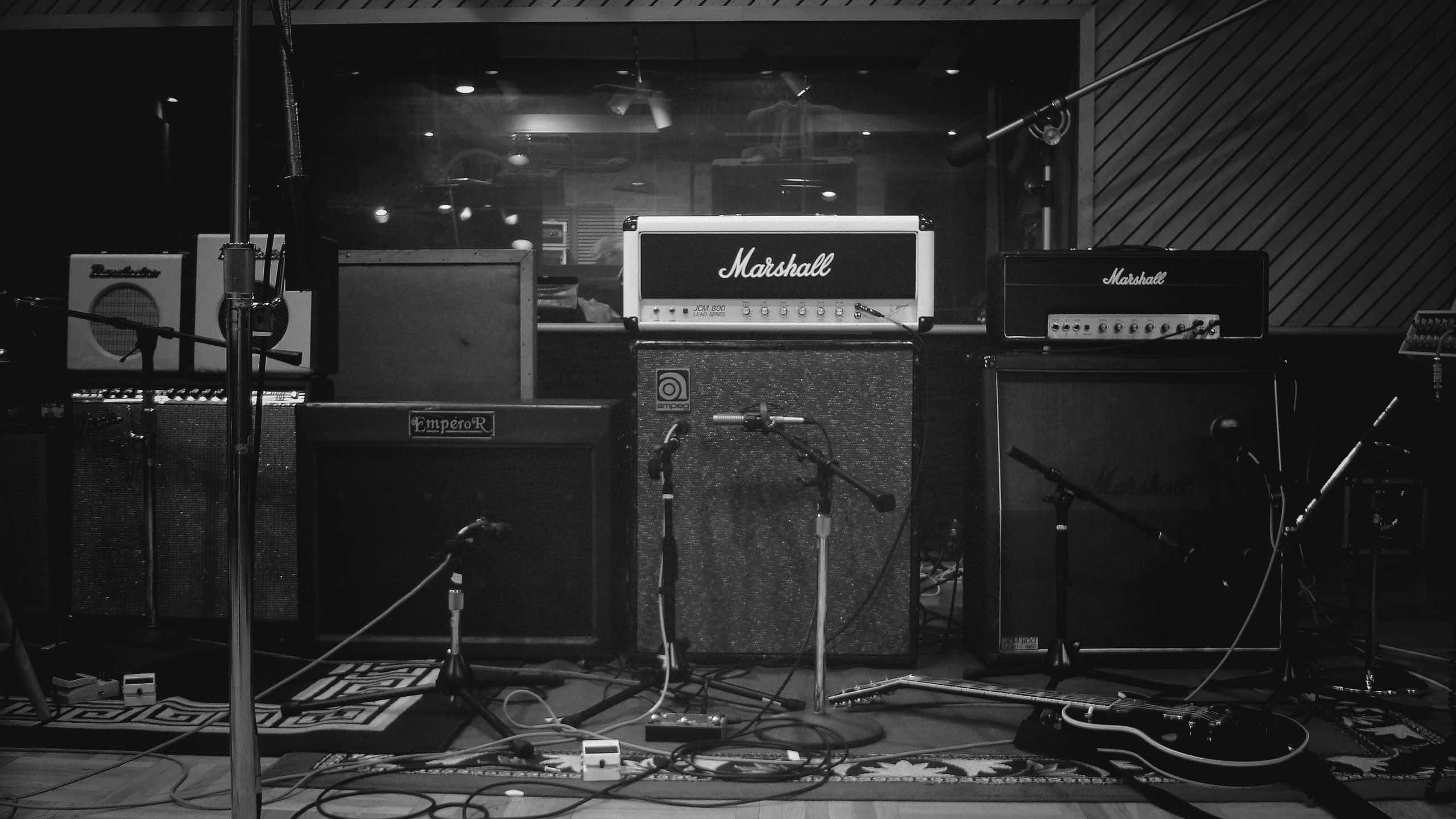 Guitar Amp 桌布 壁紙 — 音樂工作室中復古吉他擴大機和設備的黑白照片，帶有電線和麥克風。