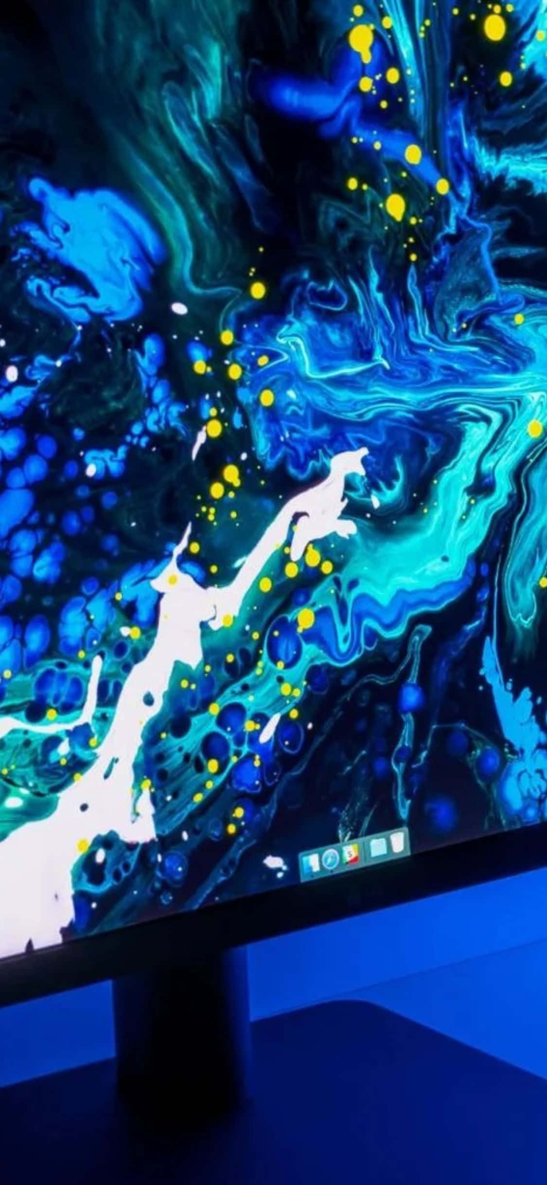 iPhone Xs Monitor 桌布 壁紙 — 顯示器展示了一件充滿活力的抽象數位藝術品，帶有旋轉的藍色、藍綠色和發光的黃色點，背景為深色。