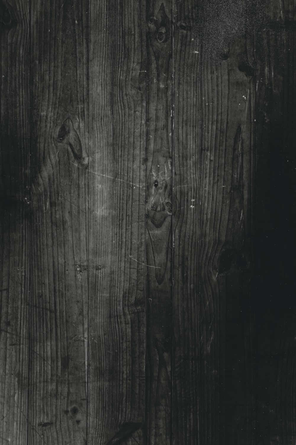 Dark Textured 桌布 壁紙 — 風化深色木板的特寫，可見木紋、節疤和刮痕，單色調。