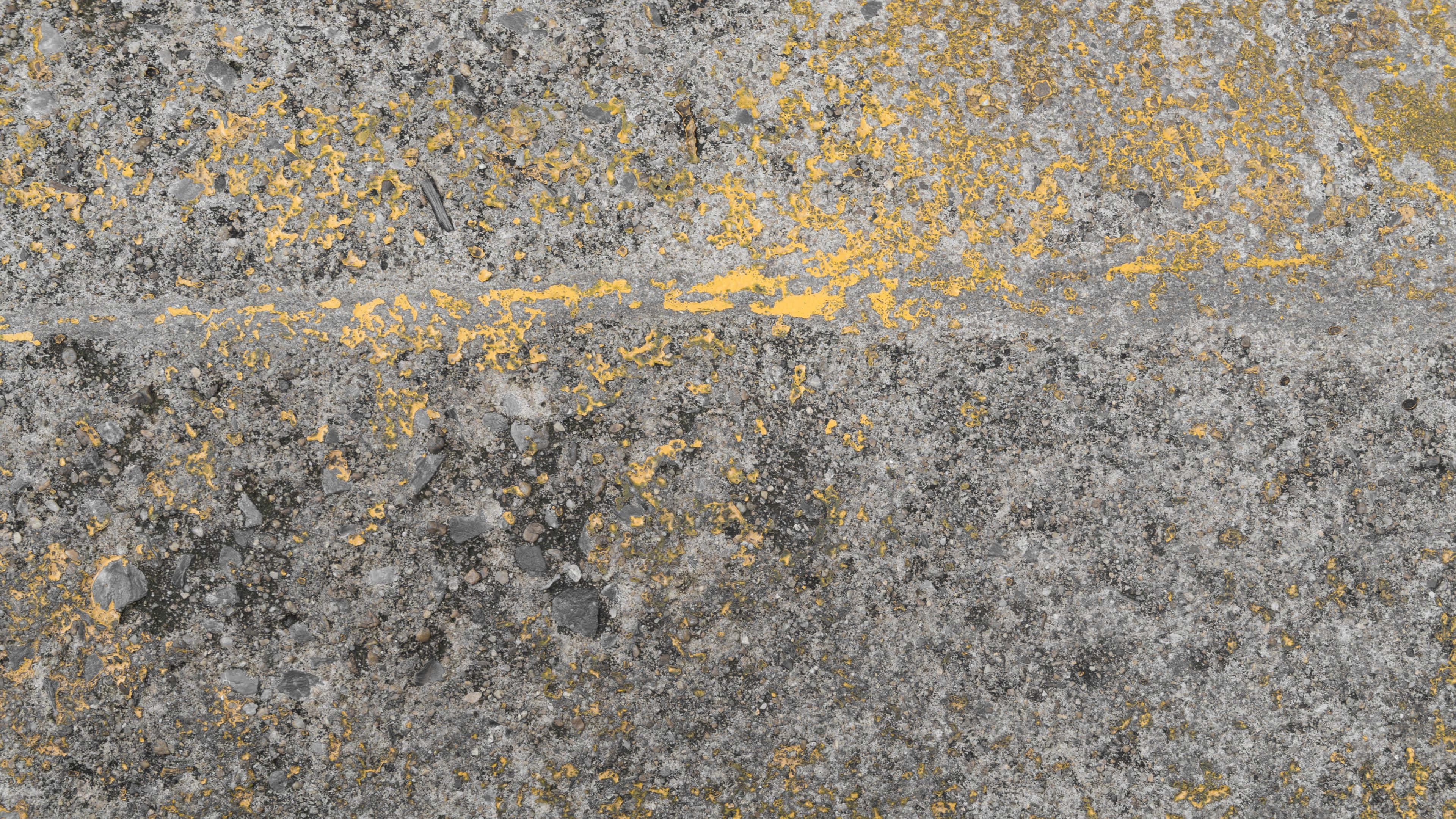 Yellow Grunge 桌布 壁紙 — 風化灰色混凝土路面的特寫，帶有褪色的黃色油漆線條和散落的碎屑。