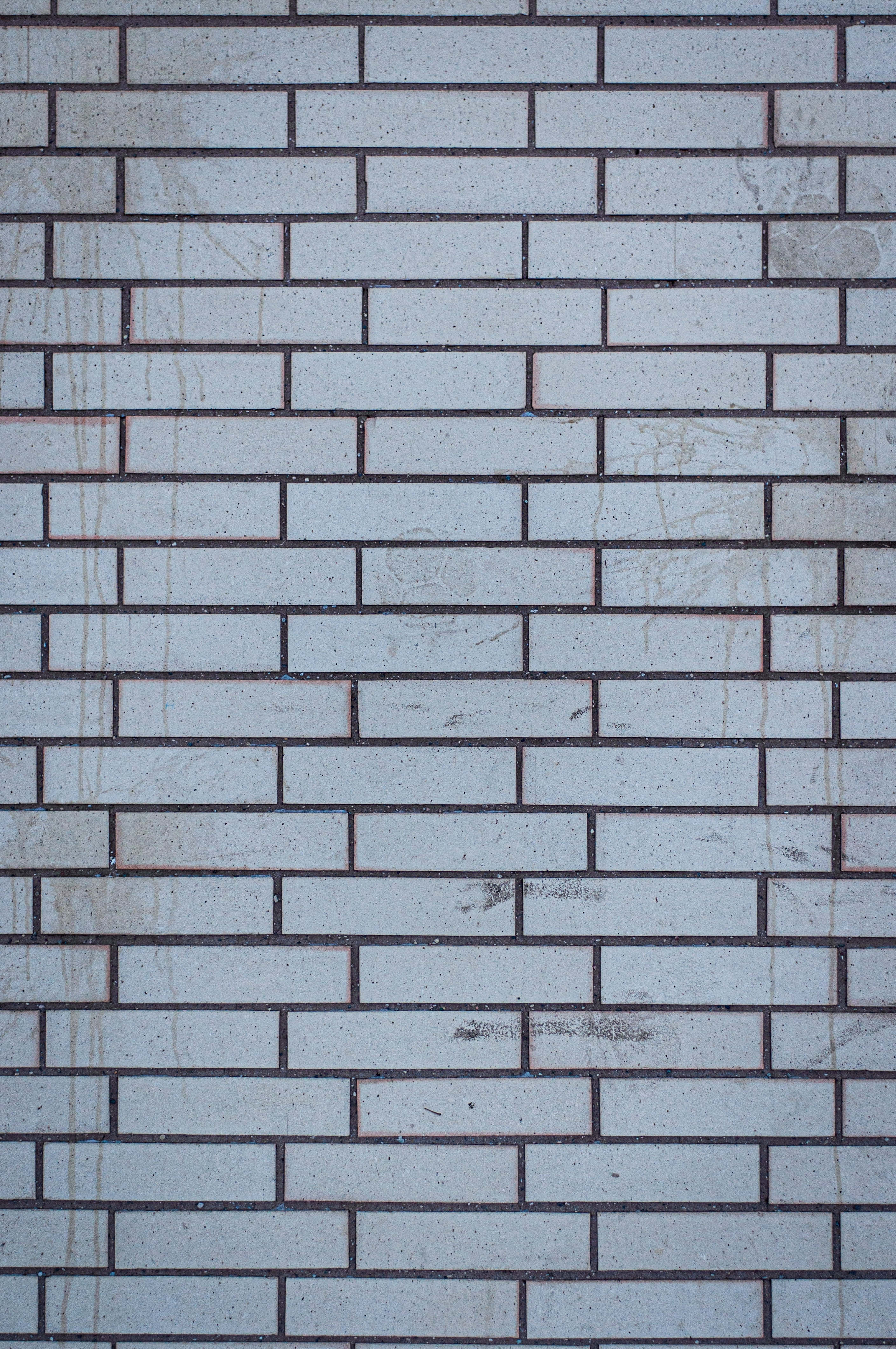 White Brick Wall 桌布 壁紙 — 風化的淺灰色磚塊特寫，帶有深色砂漿線條和淡淡污漬，形成有紋理的城市牆壁。