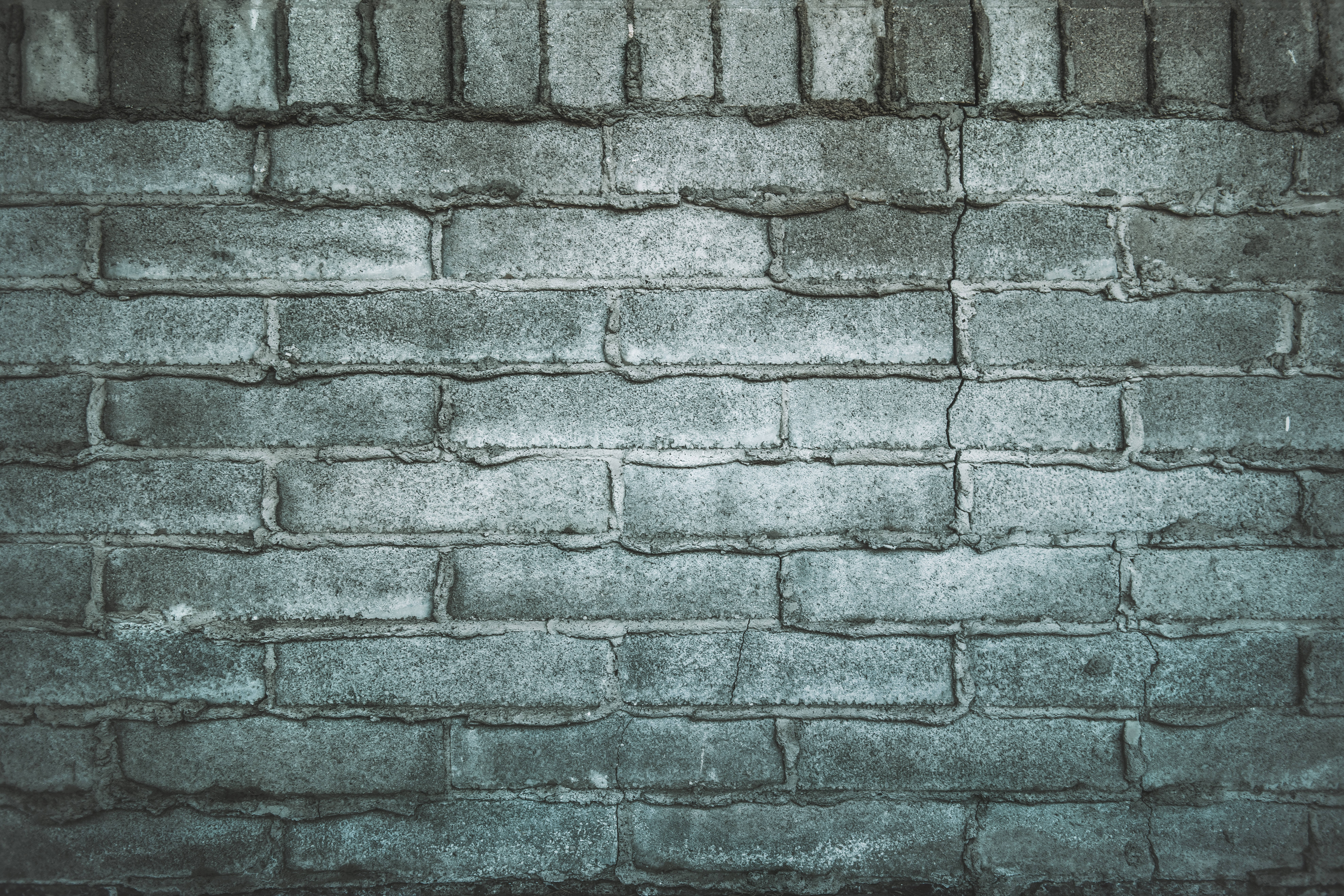 Brick 桌布 壁紙 — 風化的灰色磚牆，帶有紋理的砂漿線條，在柔和光線下呈現微妙的綠色調。
