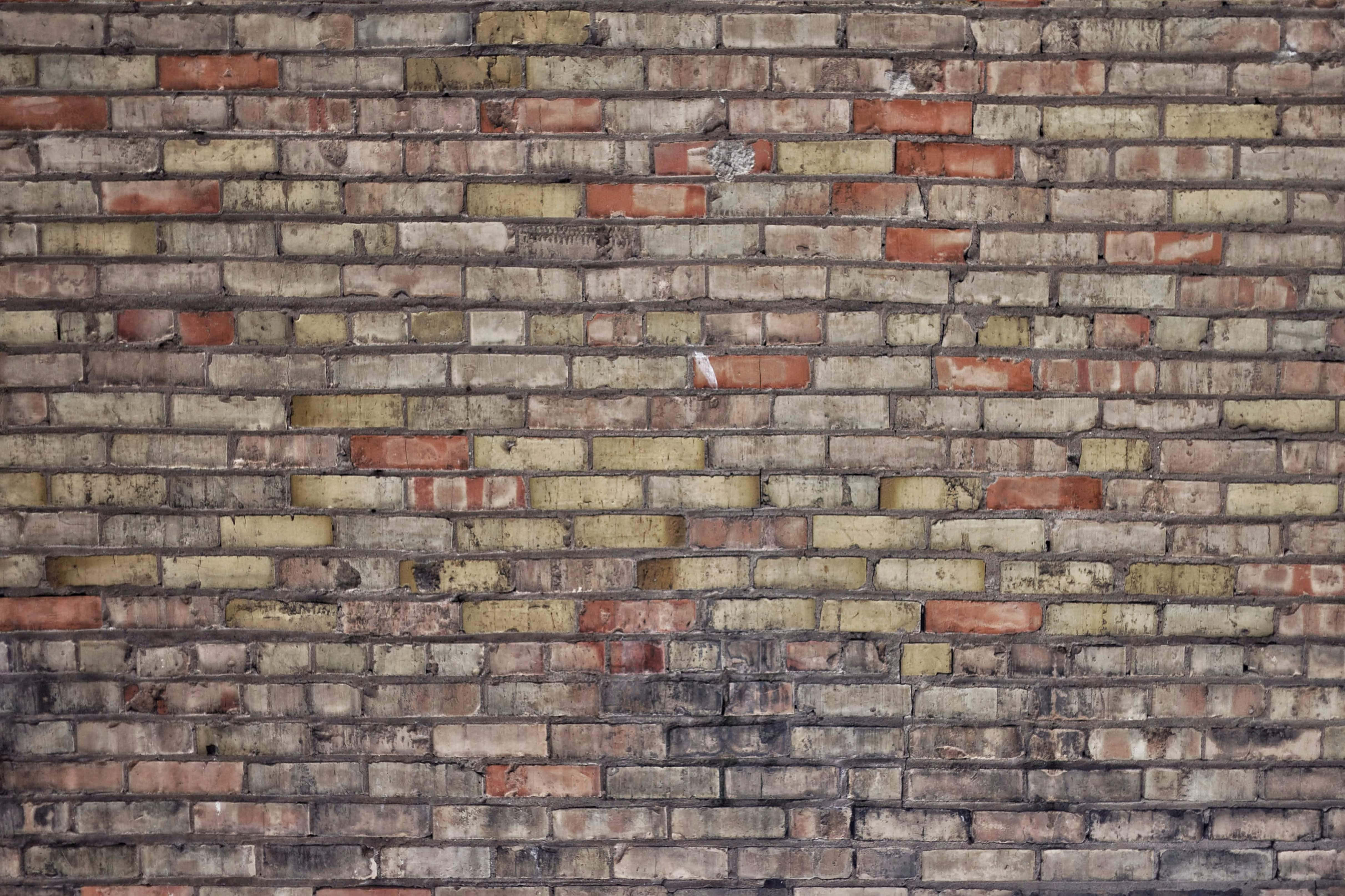Brick Wall 桌布 壁紙 — 風化磚牆的特寫，呈現多種紅色、米色和灰色色調，顯示歲月和質感。