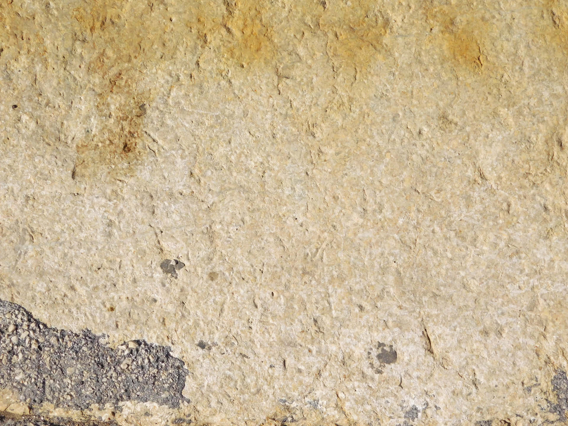Stone texture 壁紙 — 風化米色石牆的特寫，質感粗糙，左下角有深灰色斑塊。