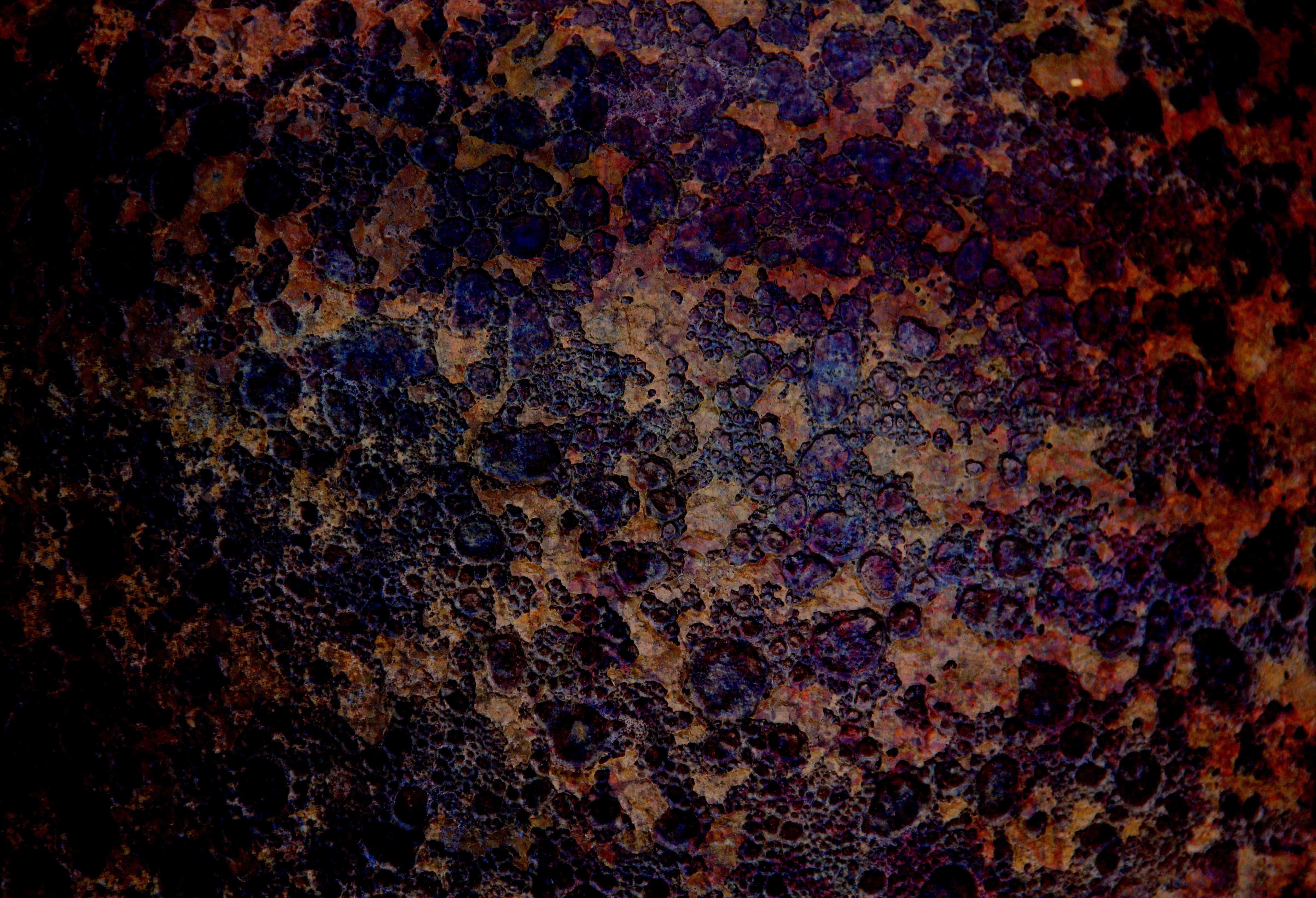 Grunge Texture 桌布 壁紙 — 風化金屬表面的特寫，帶有深層鐵鏽和深紫色銅綠，形成粗糙的紋理圖案。