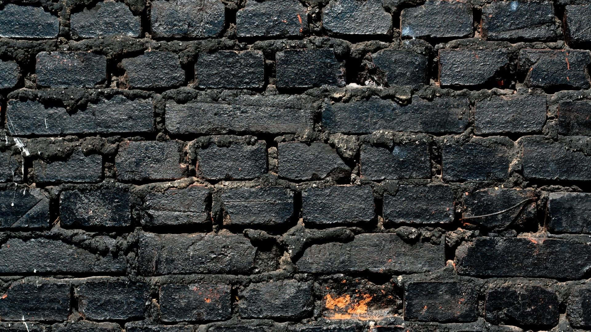 Black Brick 桌布 壁紙 — 風化黑色磚塊的特寫，裂縫灰泥和微妙的橙色污漬，營造出粗糙的城市紋理。
