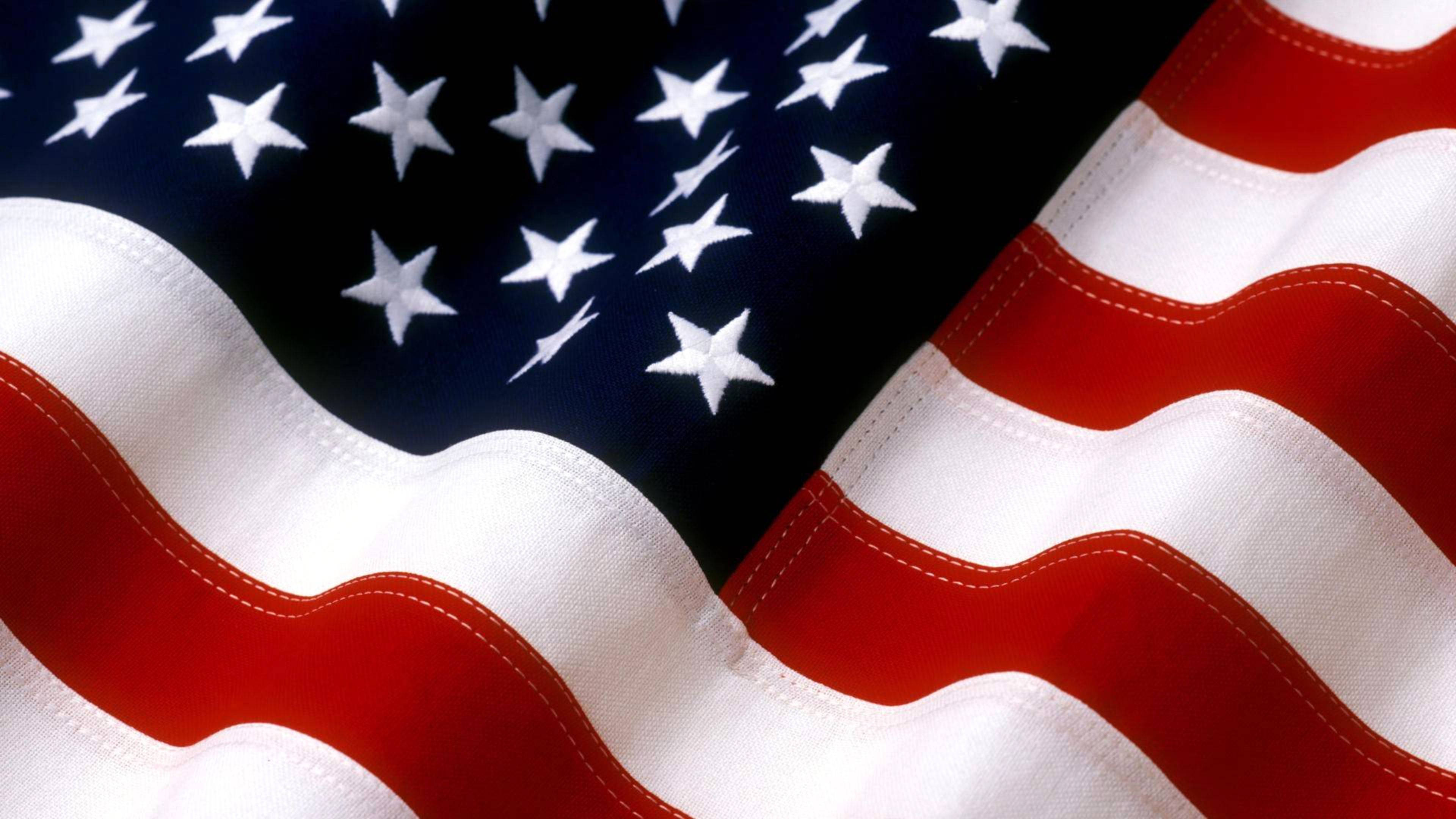 4th Of July 桌布 壁紙 — 飄揚的美國國旗特寫，顯示星星和條紋，可見布料質地和縫線。