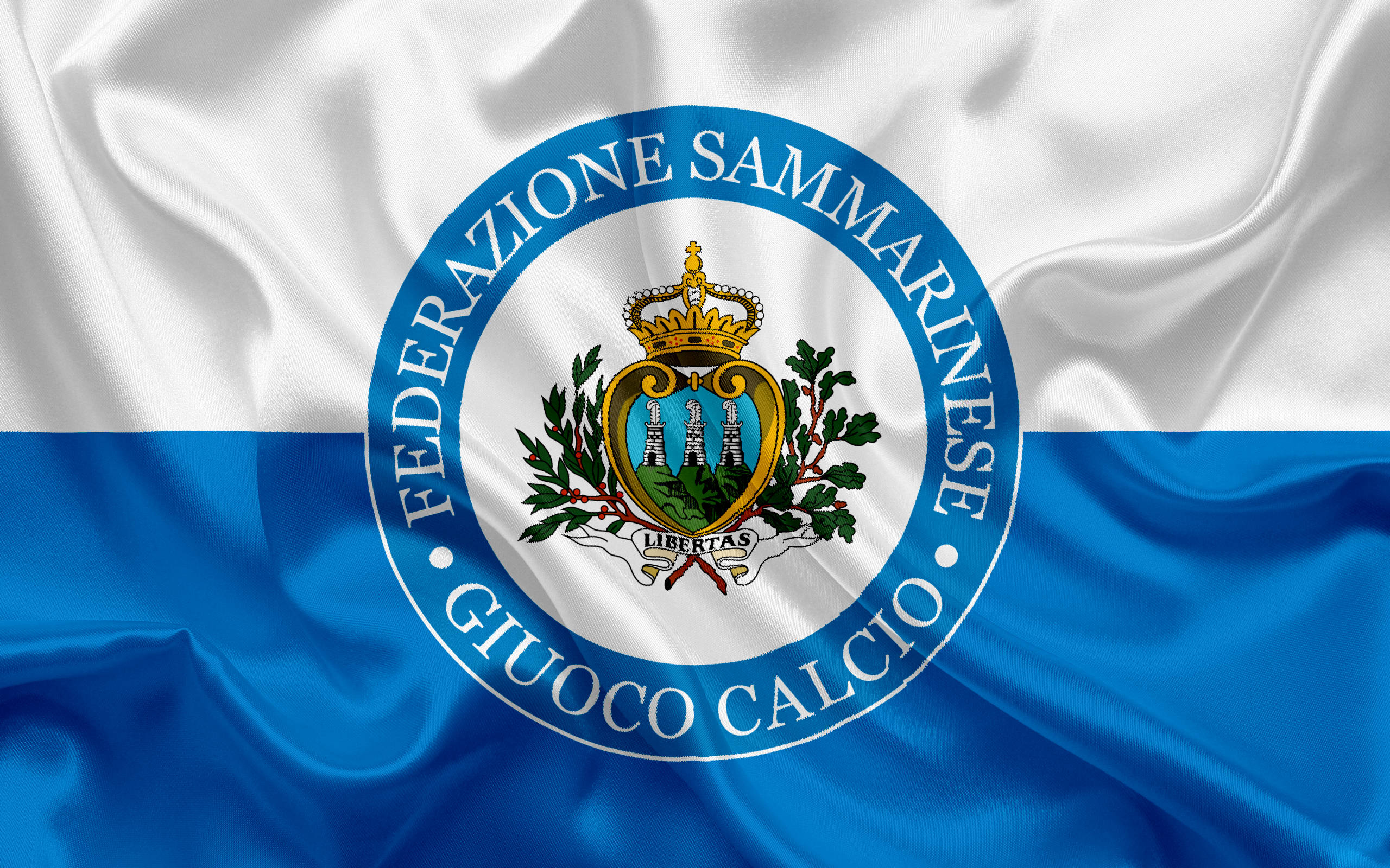 San Marino 桌布 壁紙 — 飄揚的聖馬力諾足球協會旗幟，帶有藍白條紋和中央徽章，徽章上有皇冠、月桂花環和塔樓。