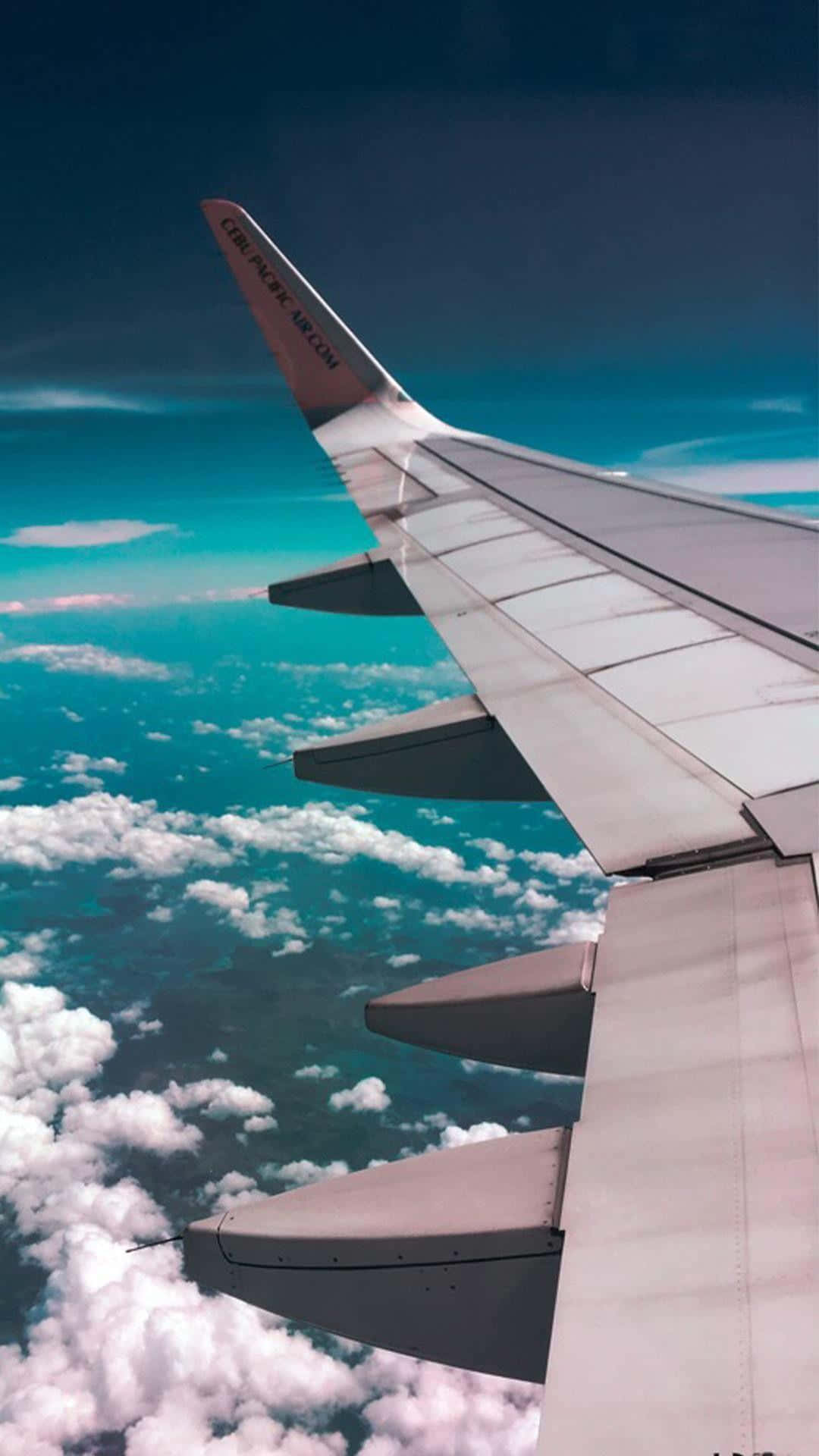 Travel Aesthetic Phone 桌布 壁紙 — 飛機機翼伸展在蓬鬆的白雲之上，映襯著充滿活力的藍綠色天空。