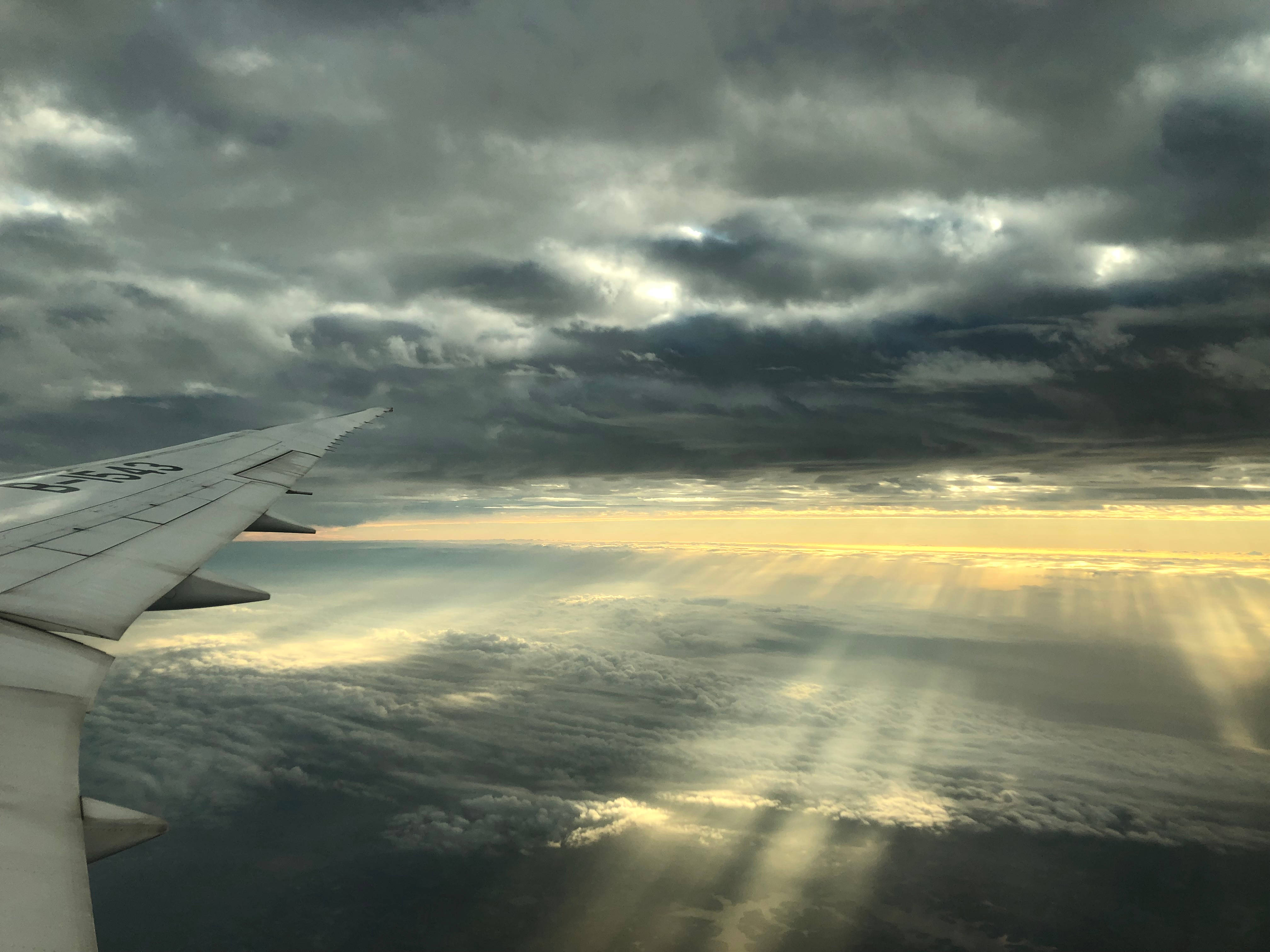 Plane 桌布 壁紙 — 飛機機翼劃破戲劇性的暴風雲，金色陽光在日落時穿透而出。