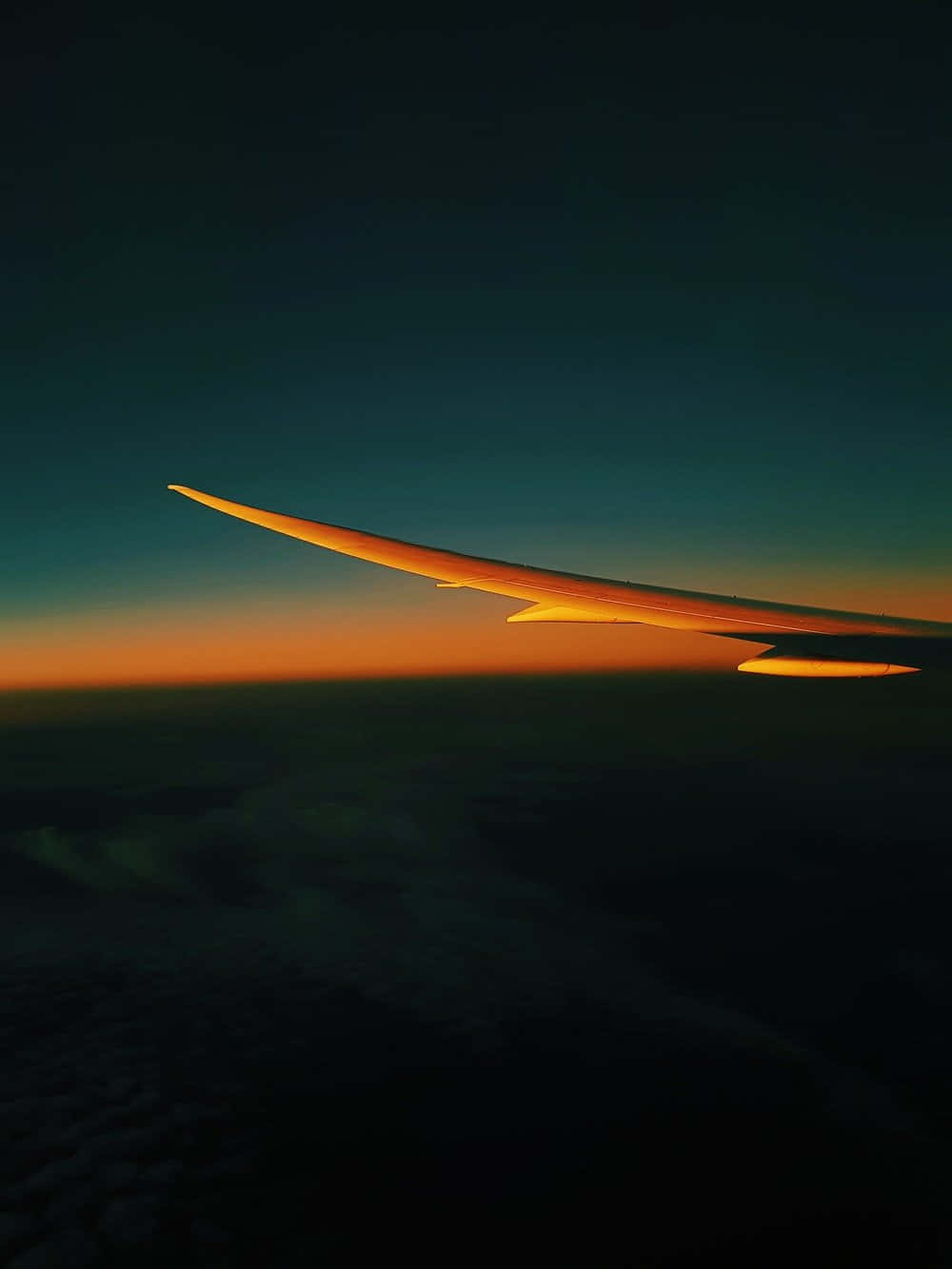 Ambience 桌布 壁紙 — 飛機機翼在暮色天空中閃爍琥珀色光芒，飛機在日落時分飛越雲層。