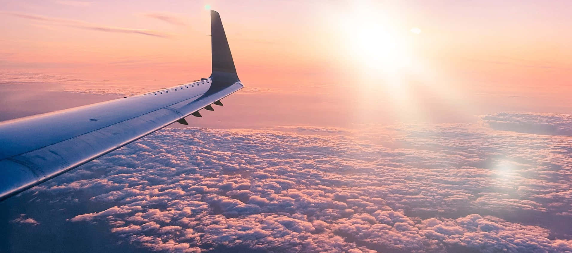 Aviation 桌布 壁紙 — 飛機機翼在沐浴著金色日出光芒的棉花糖雲層上方滑翔。