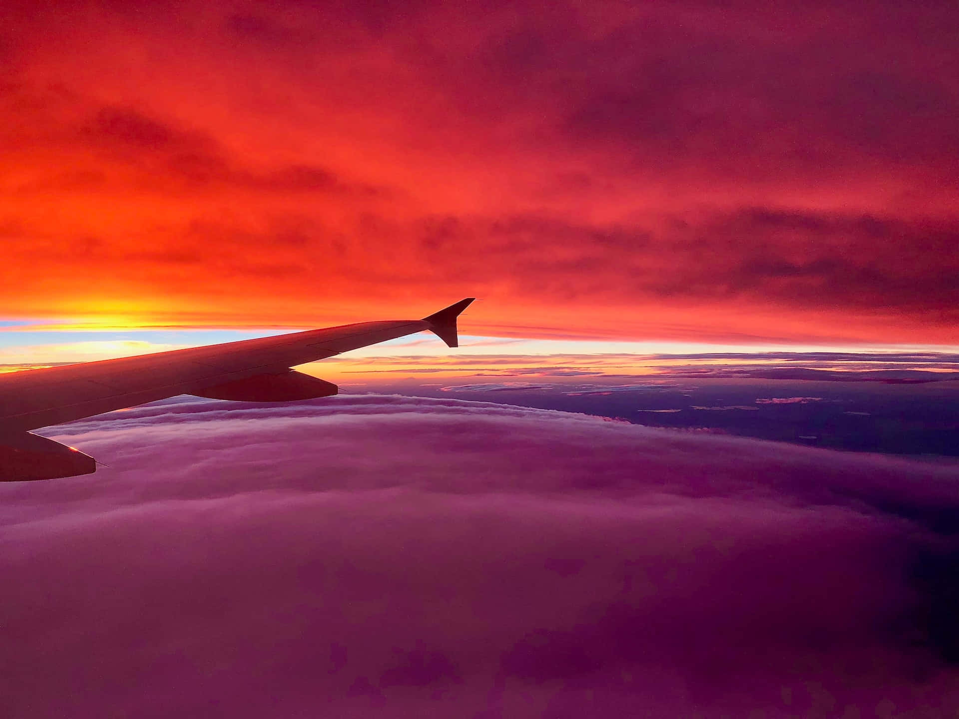 Peaceful Relaxing 桌布 壁紙 — 飛機機翼在紫色雲海之上，襯著熾熱的日落天空形成剪影。