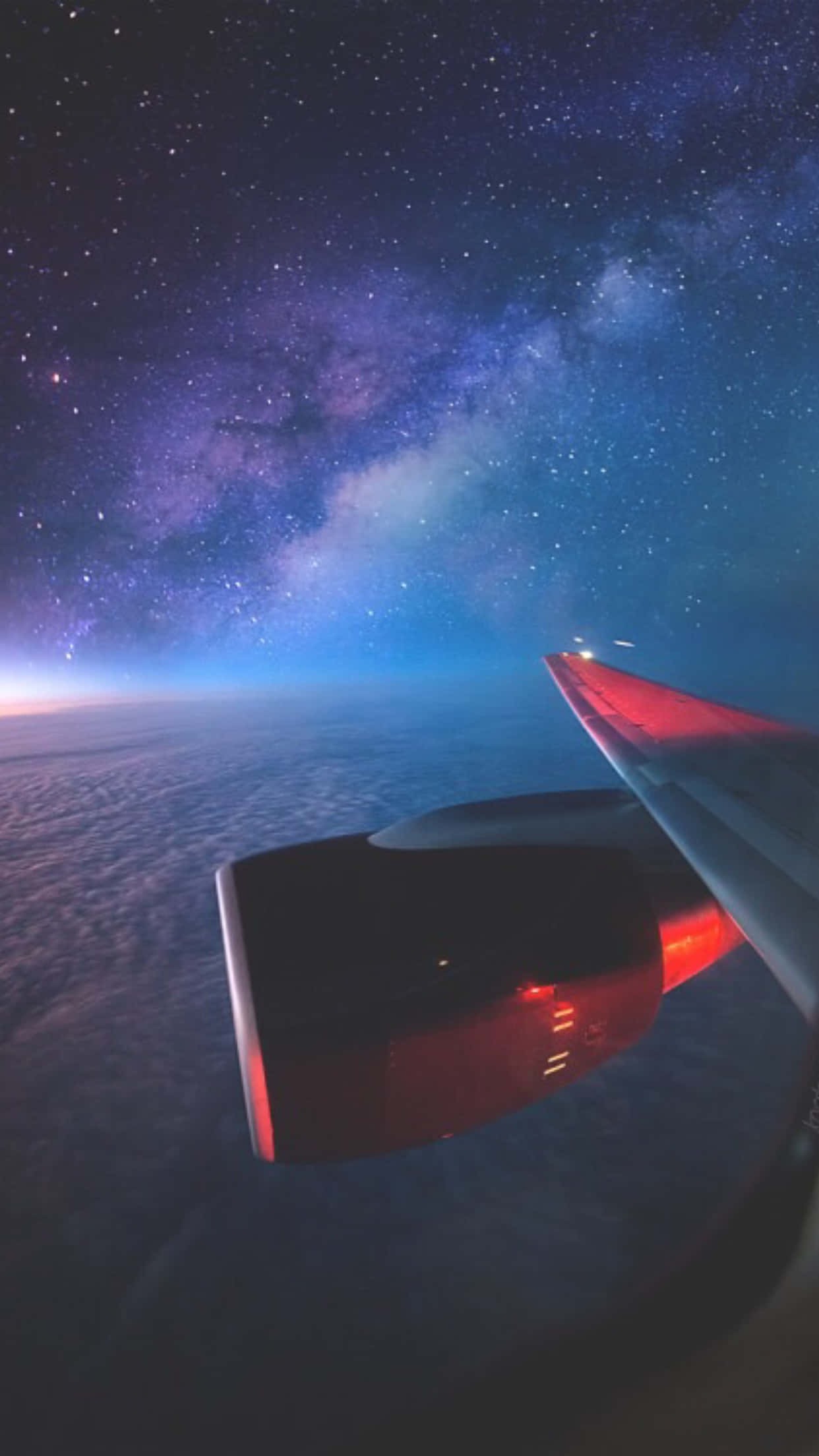 夜空 桌布 壁紙 — 飛機機翼在繁星點點的夜空下發出紅光，上方有銀河，下方有雲層。