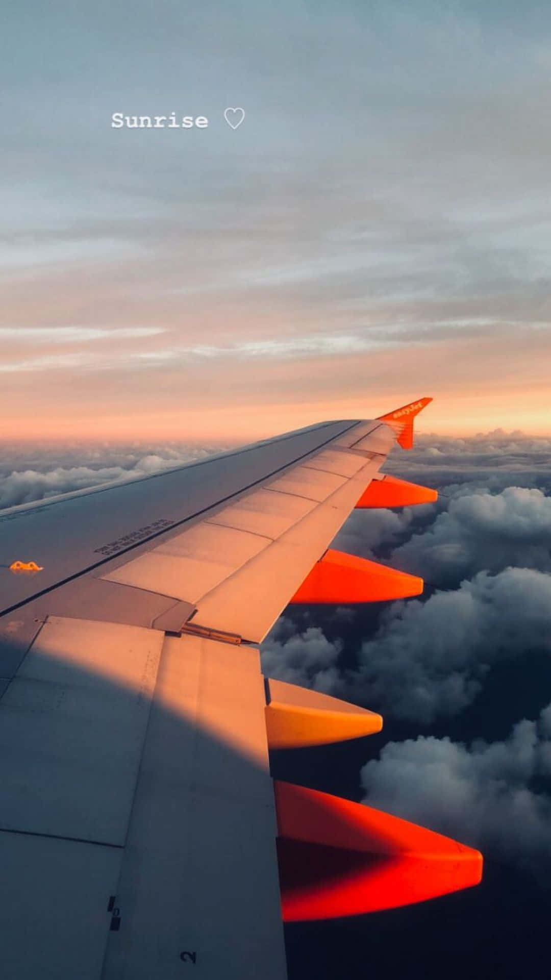 飛機 桌布 壁紙 — 飛機機翼在蓬鬆的雲層上方滑翔，日出將天空染成溫暖的橙色和粉紅色調。