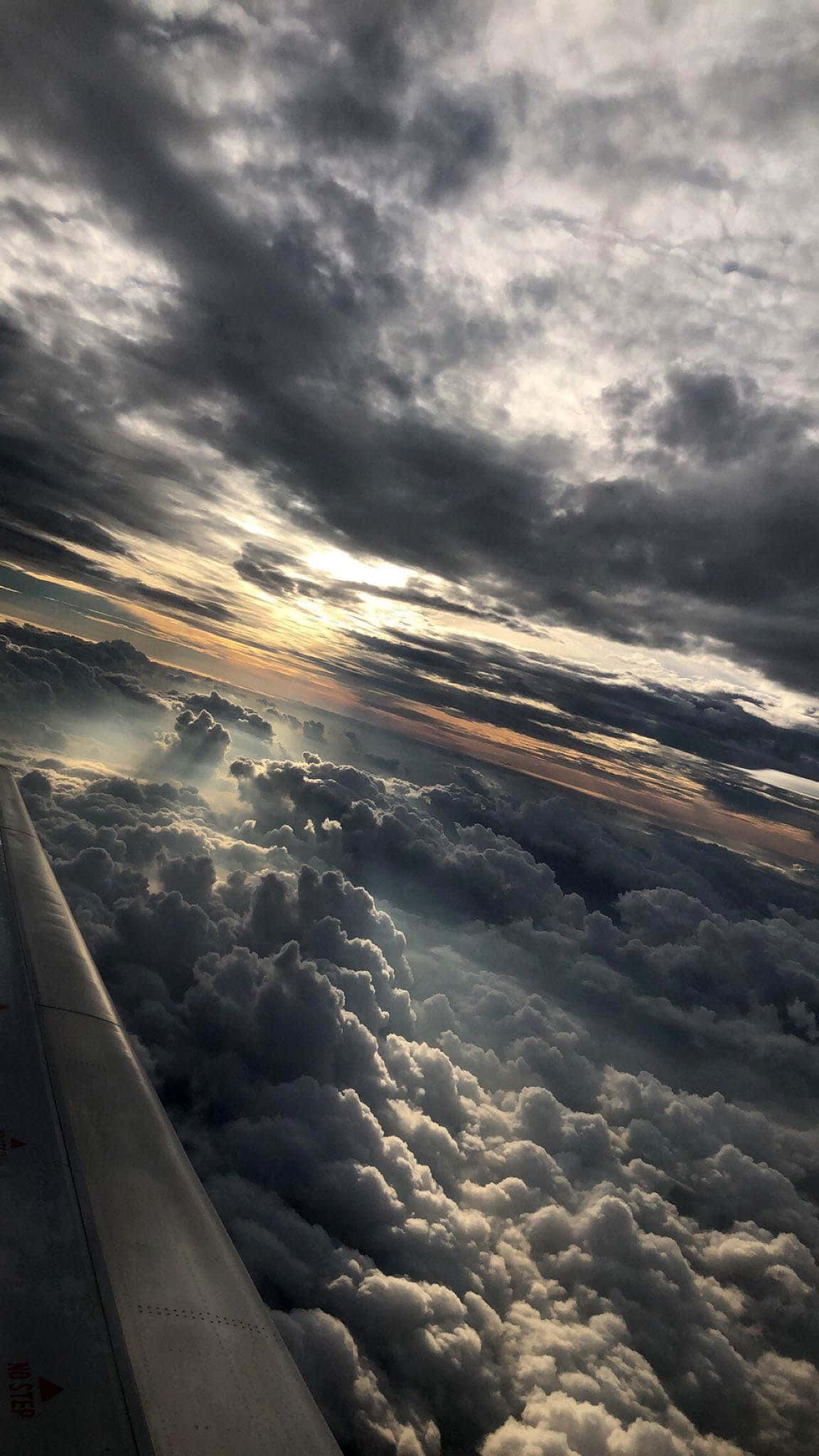 雲朵 桌布 壁紙 — 飛機機翼在蓬鬆雲海上滑翔，金色夕陽穿透黑暗的暴風雲。