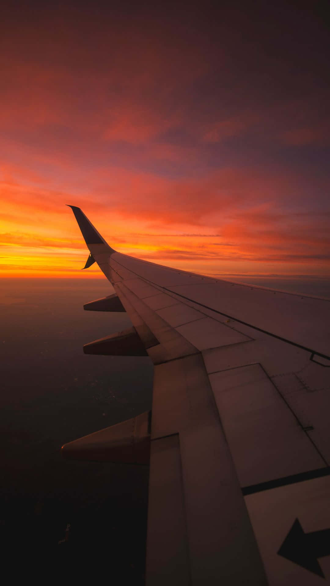 飛機 桌布 壁紙 — 飛機機翼在雲層上方火熱的橙紅色日落天空襯托下形成剪影。