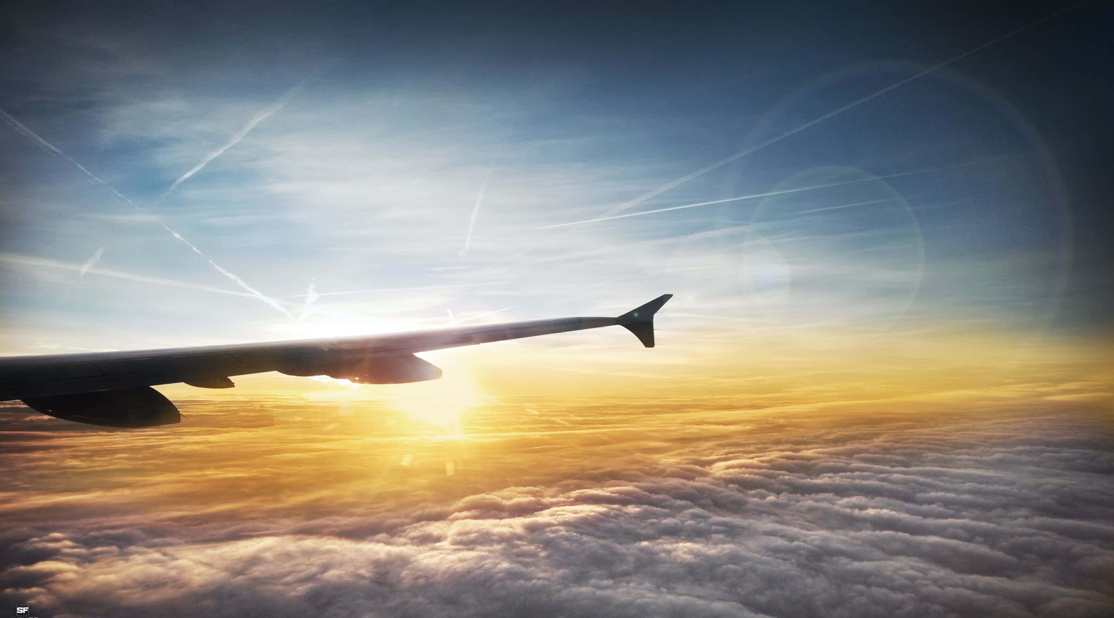4K 飛機壁紙 桌布 壁紙 — 飛機翼剪影映襯著從雲層上方穿透的金色日出。