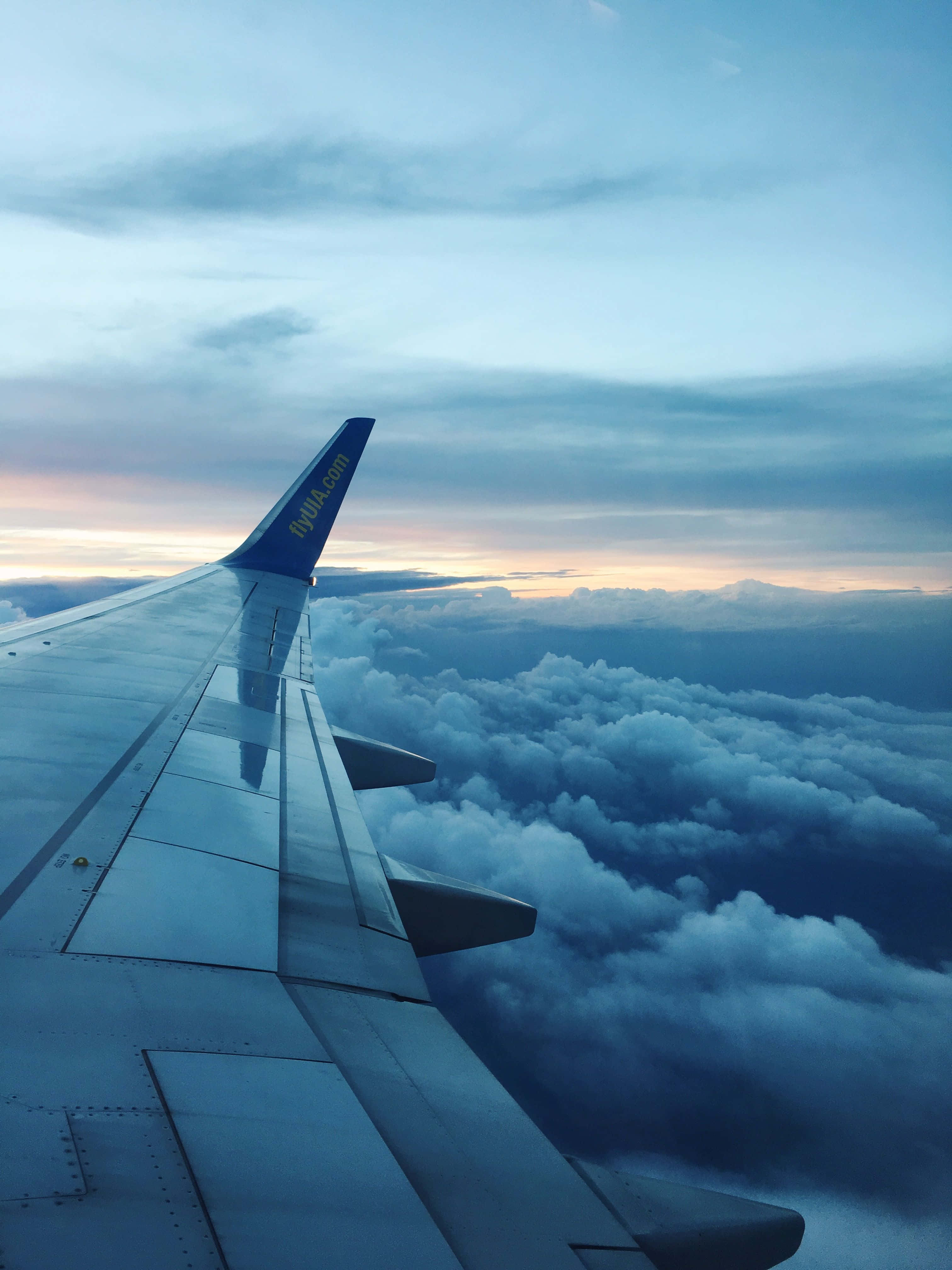 Plane 桌布 壁紙 — 飛機翼在黃昏時伸展在雲海之上，天空帶有柔和的粉紅和藍色調。
