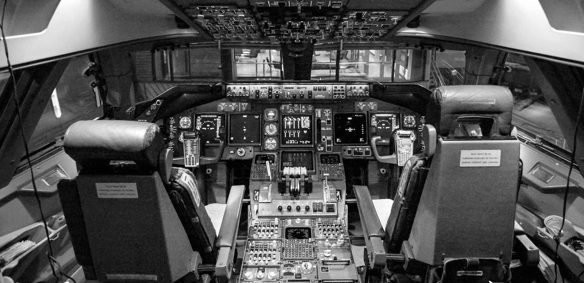 Aviation 桌布 壁紙 — 飛機駕駛艙的黑白照片，設有兩個飛行員座椅和複雜的儀表板。
