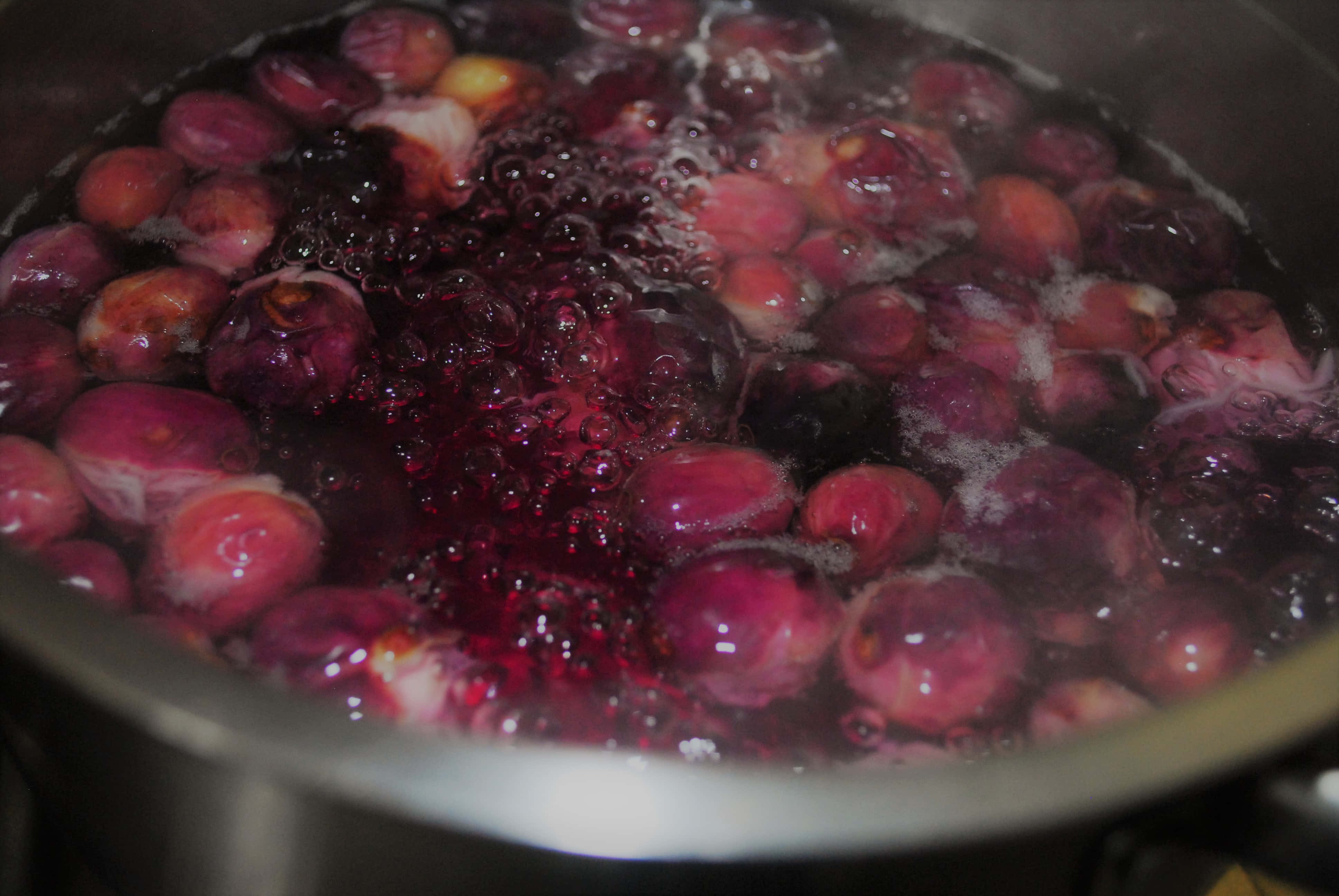 boil 桌布 壁紙 — 飽滿的紫色李子在不鏽鋼鍋中燉煮，釋放出鮮活的果汁和蒸汽。